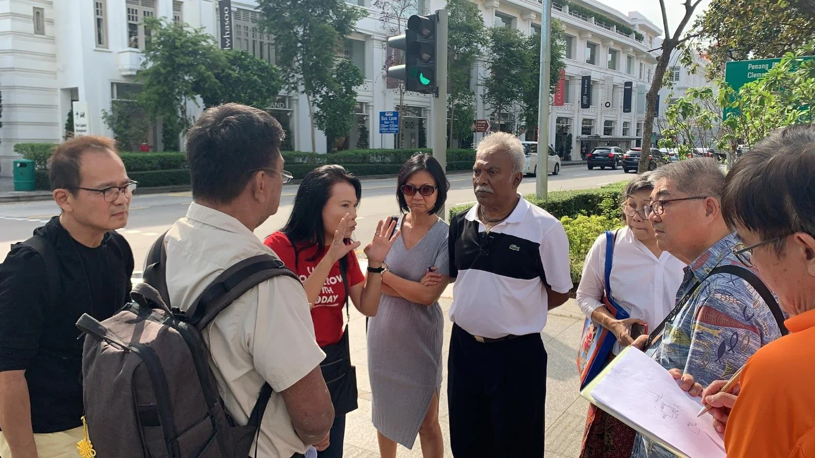 A group of Tourist Guides gathered outside CAPITOL Singapore engaged in a discussion.