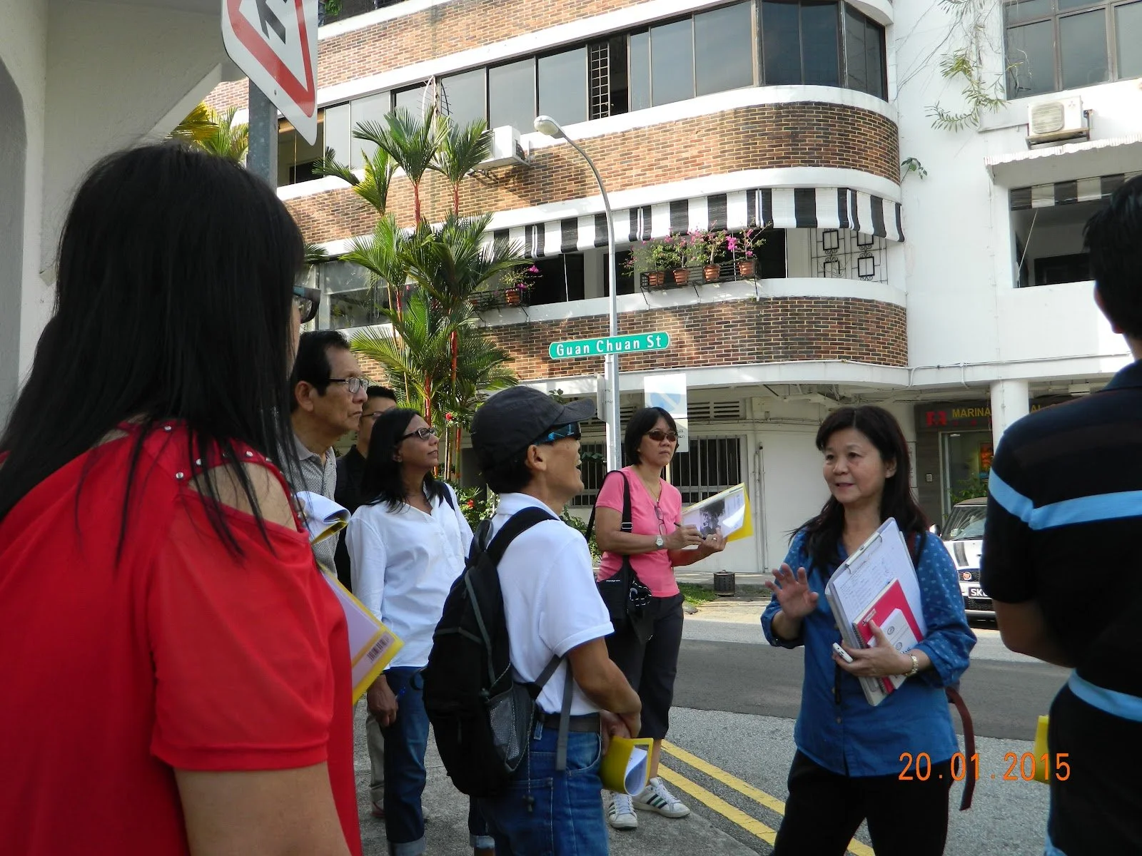 Group of Tourist Guides standing on a street corner with a street sign reading 'Guan Chuan St' in the background.