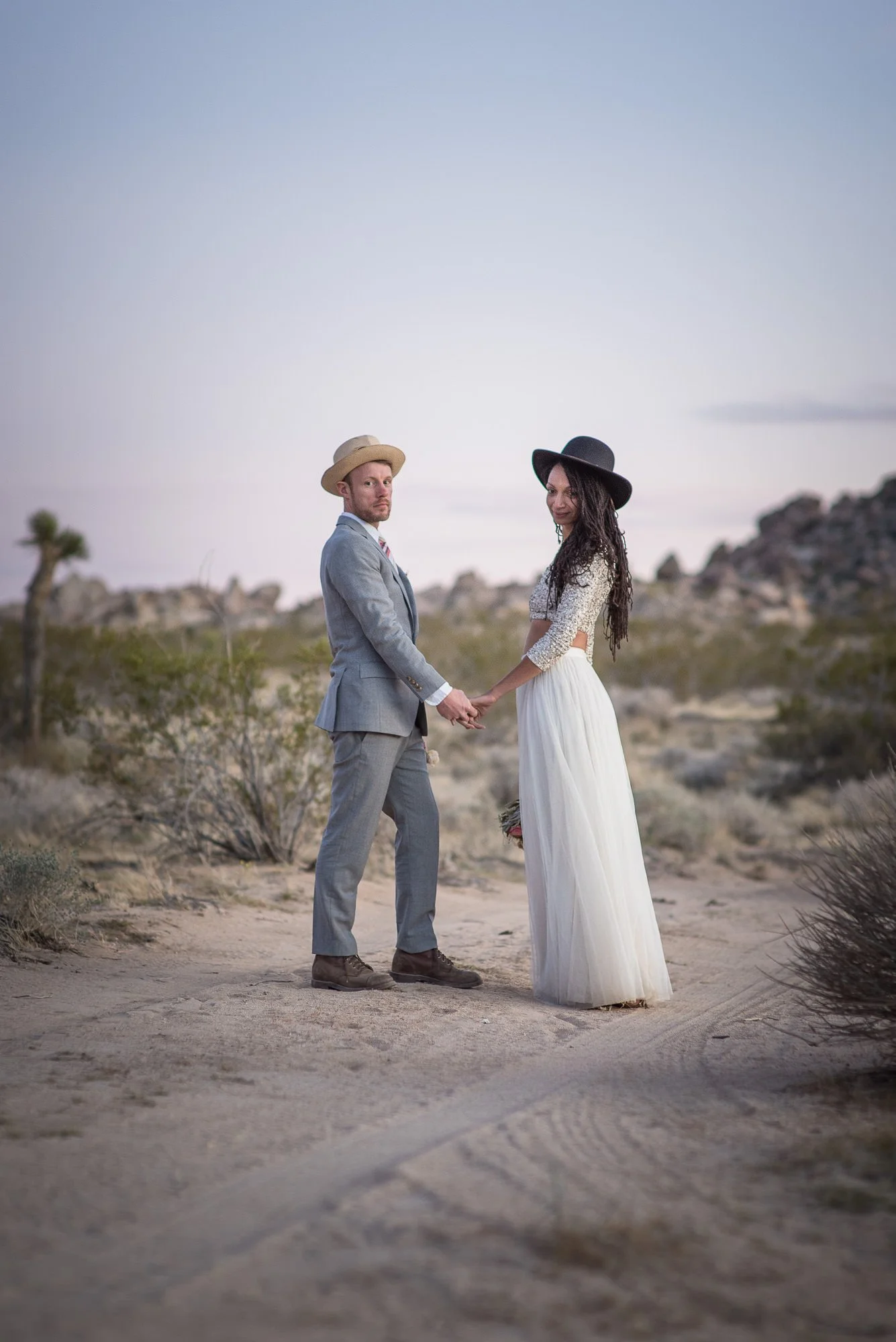 Bride and groom standing against a rugged mountain backdrop during desert elopement