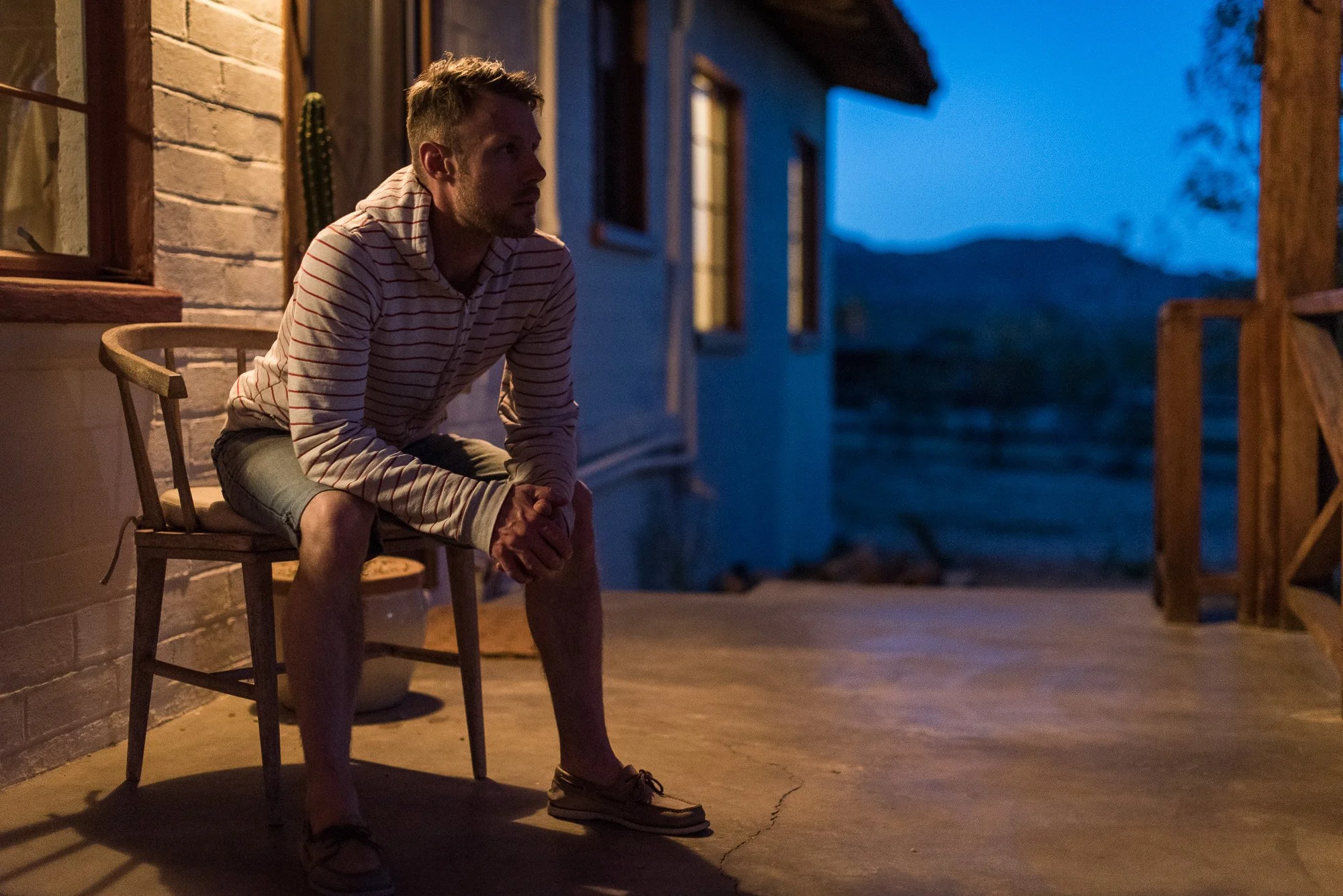 Groom sitting on porch at sunset in quiet reflection before his Joshua Tree wedding