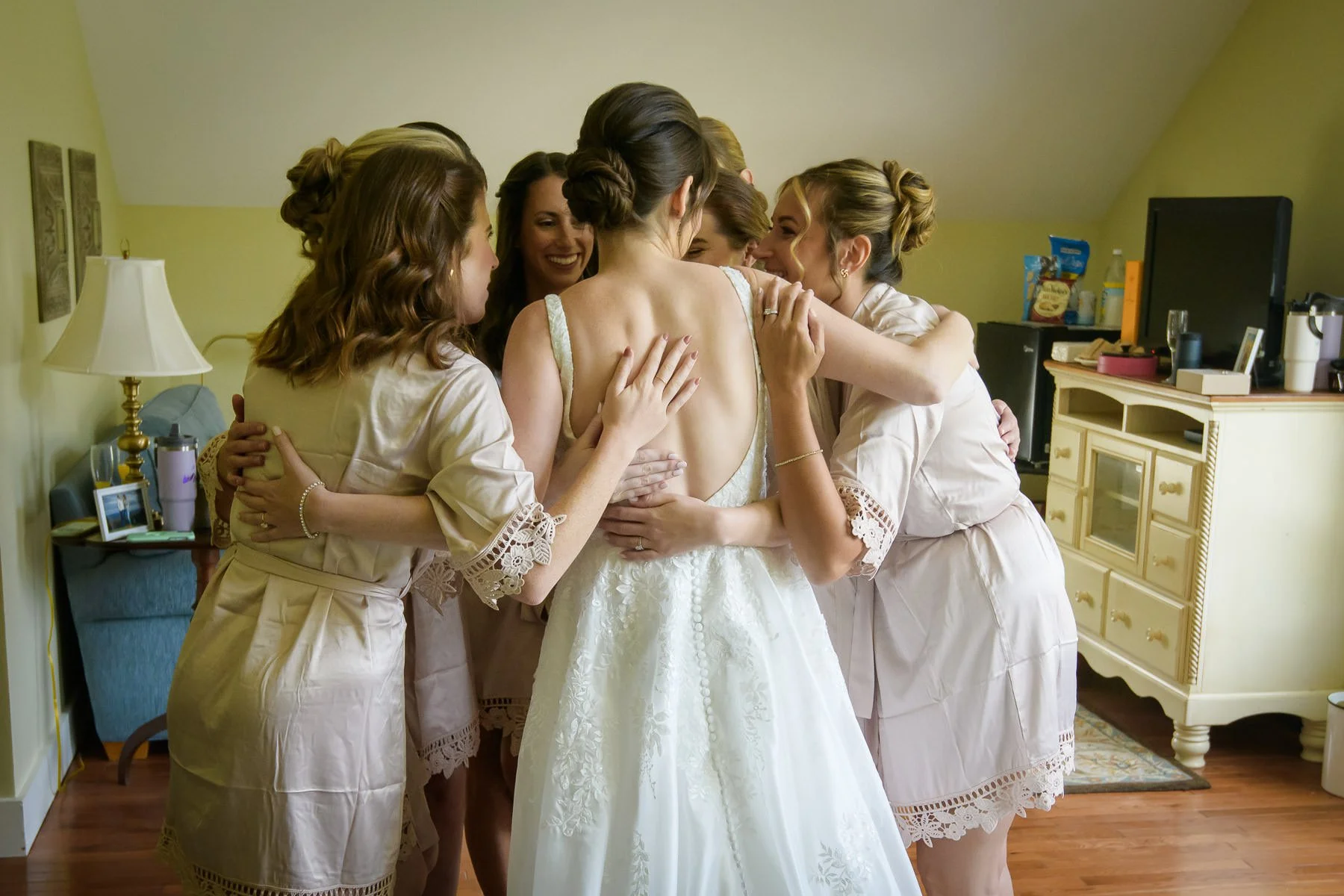 Chelsea shares a group hug with her bridesmaids while getting ready at the Inn at Manchester in Vermont. The moment captures a warm, emotional pause before the wedding ceremony.