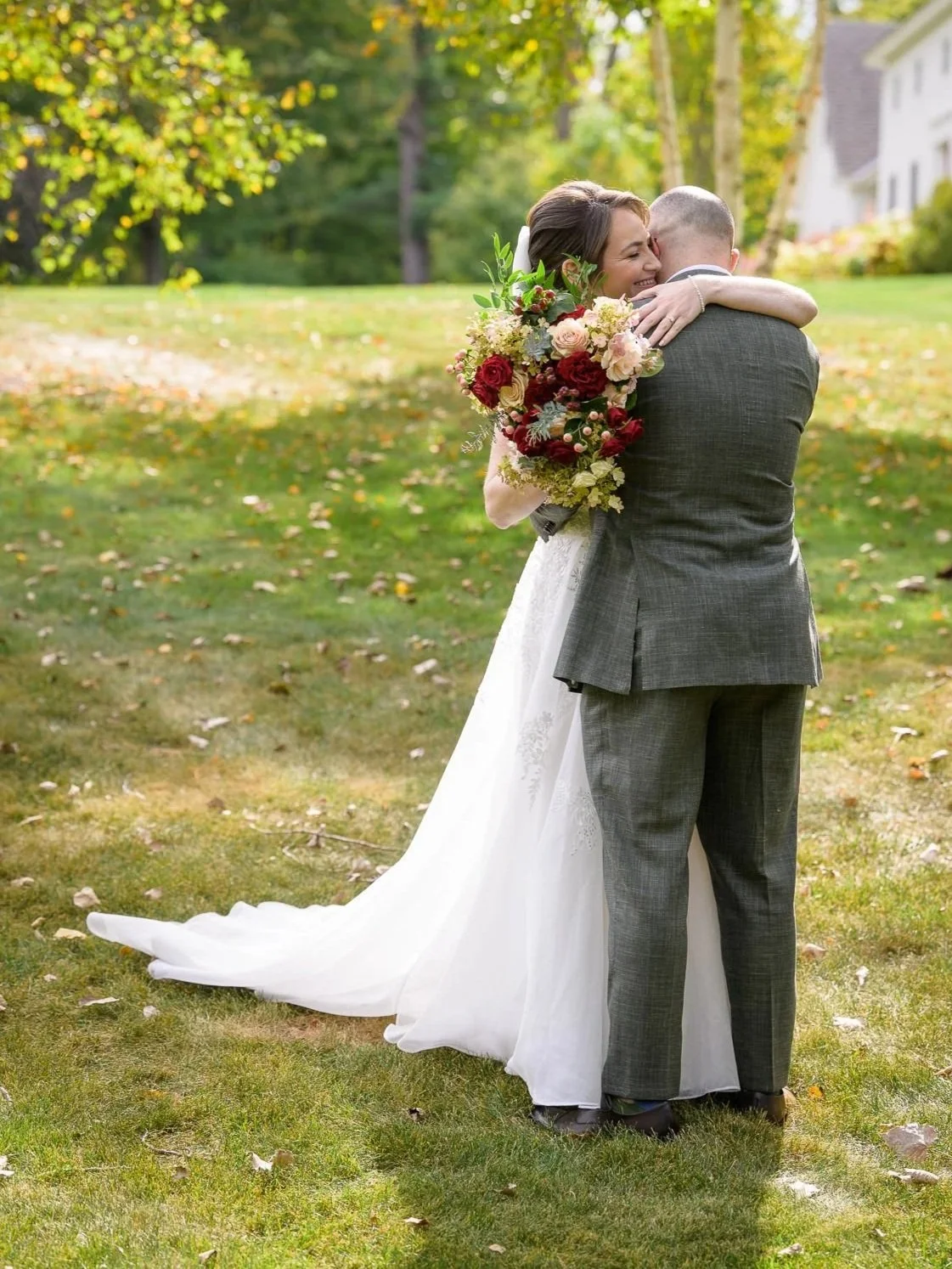 Chelsea and David embrace during their first look on the lawn at the Inn at Manchester in Vermont. Chelsea smiles over David’s shoulder while holding her bouquet in a quiet, emotional moment before the ceremony.