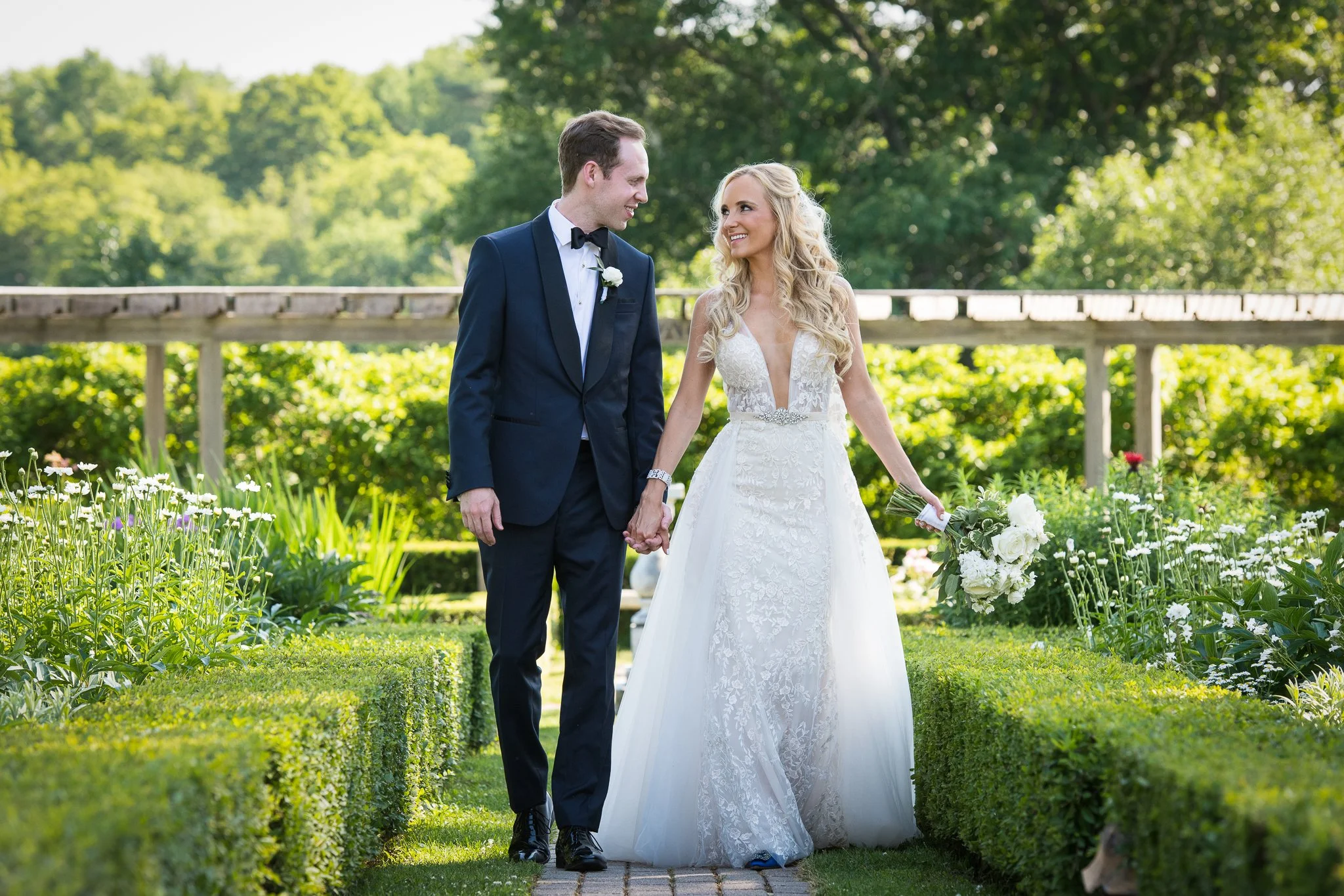 Wedding couple walking hand in hand through the gardens at Hildene, The Lincoln Family Home in Manchester, Vermont. A natural, directed portrait moment