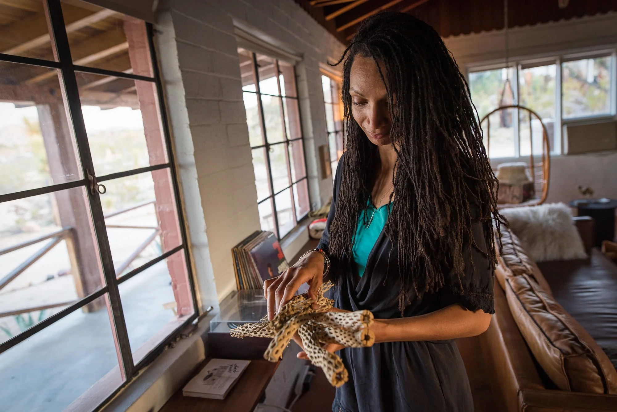 Bride holding cholla cactus while getting ready inside desert Airbnb before Joshua Tree elopement