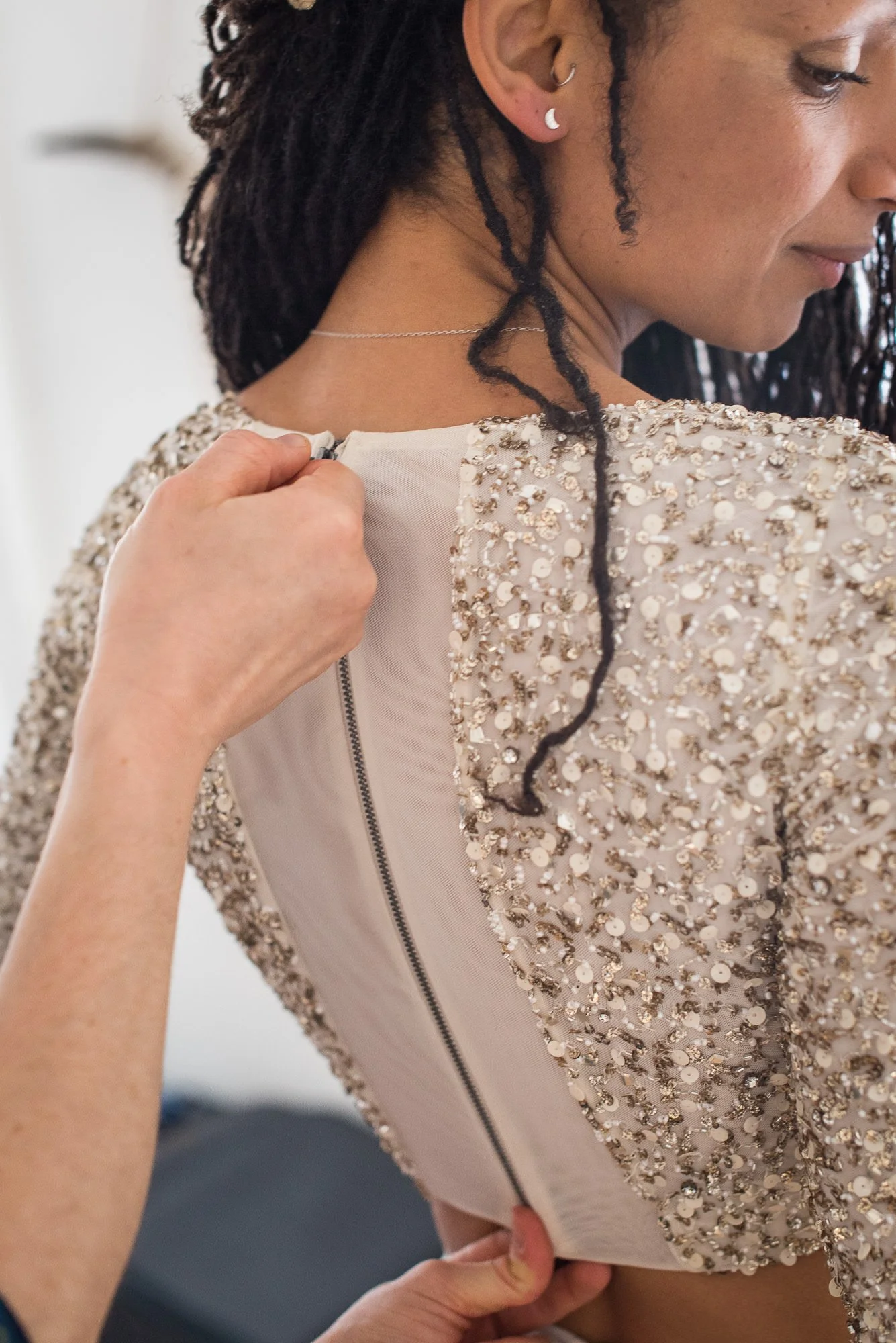 Fastening the back of bride's beaded wedding gown before eloping in Joshua Tree