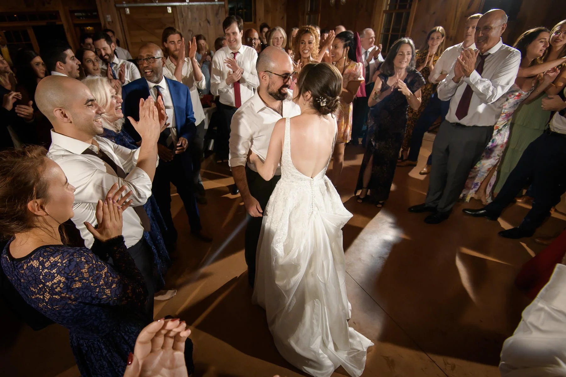 Chelsea and David dance together on the reception dance floor at the Inn at Manchester in Vermont, surrounded by cheering guests in a circle. The image captures the warmth, energy, and joy of the celebration.