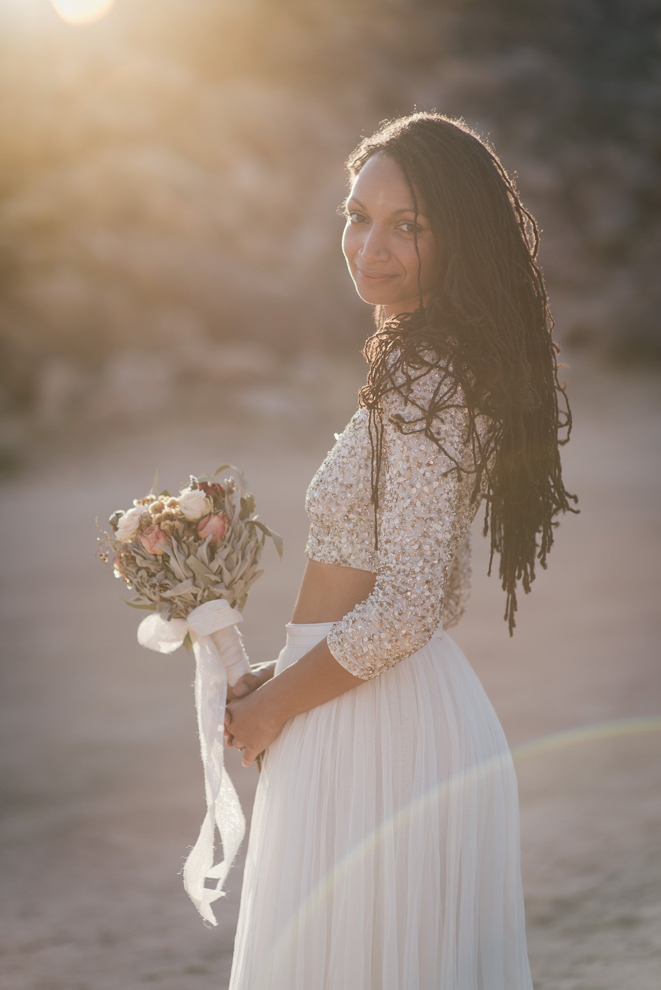 Bride holding bouquet in soft sunset light before elopement ceremony in Joshua Tree