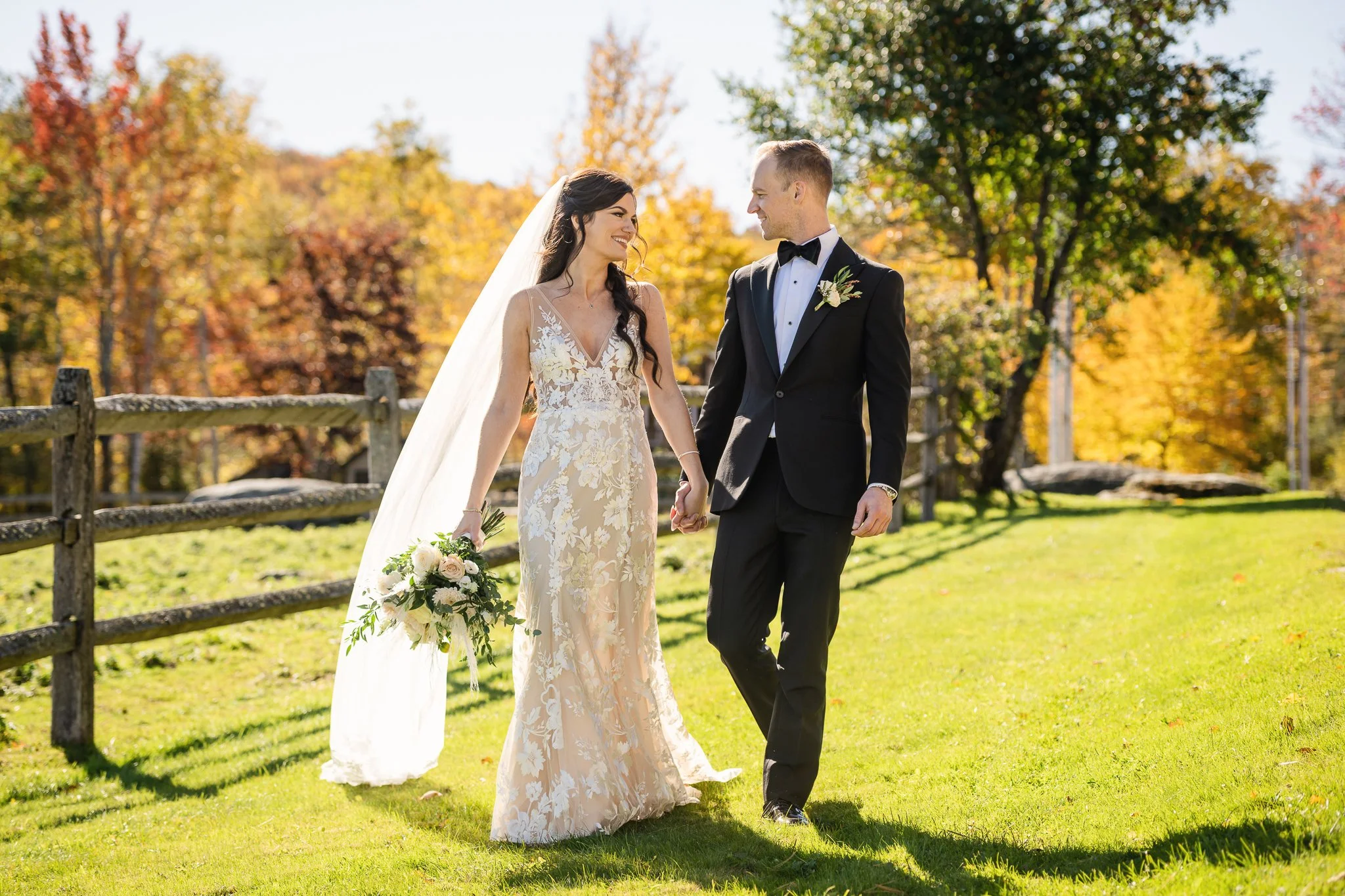 Wedding couple walking hand in hand through autumn foliage at Mountain Top Resort in Chittenden, Vermont. A relaxed, natural portrait moment