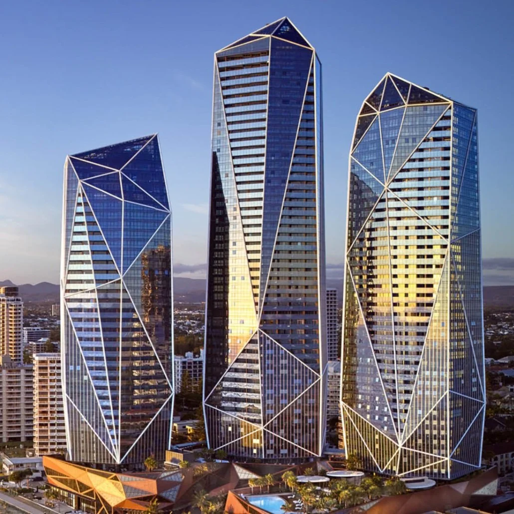 Three modern skyscrapers with geometric designs and reflective glass surfaces in a cityscape during sunset.