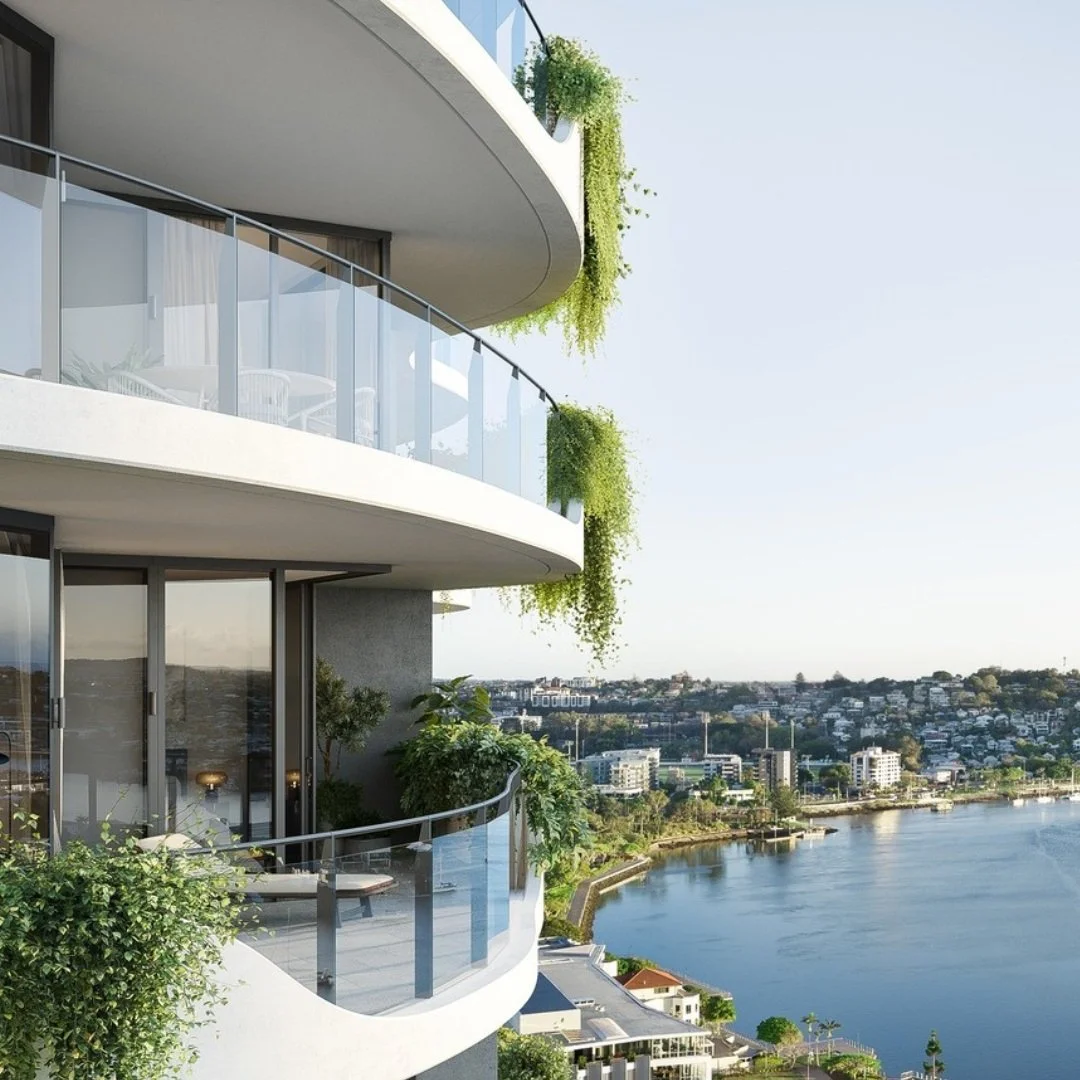 Modern apartment building with glass balconies decorated with green plants overlooking a river and cityscape.