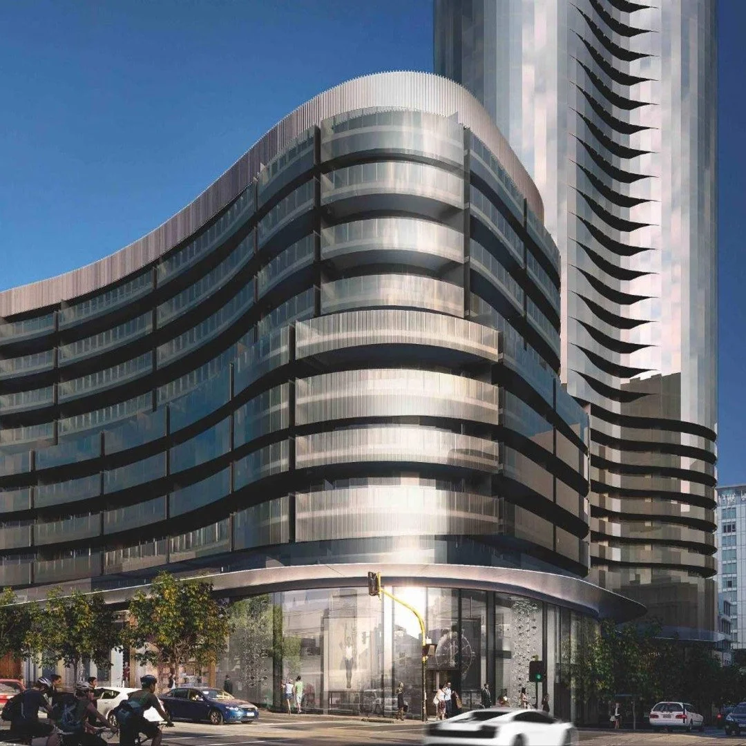 Modern high-rise building with curved balconies and glass exterior, street scene with cars and pedestrians, clear blue sky.