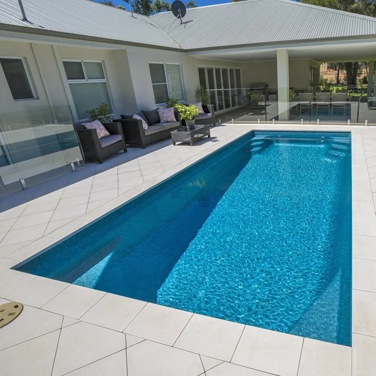 Swimming pool with deck chairs and potted plants outside a house with a screened porch.