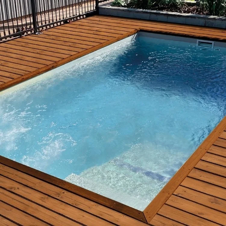 Swimming pool with blue water surrounded by a wooden deck and black metal fence.