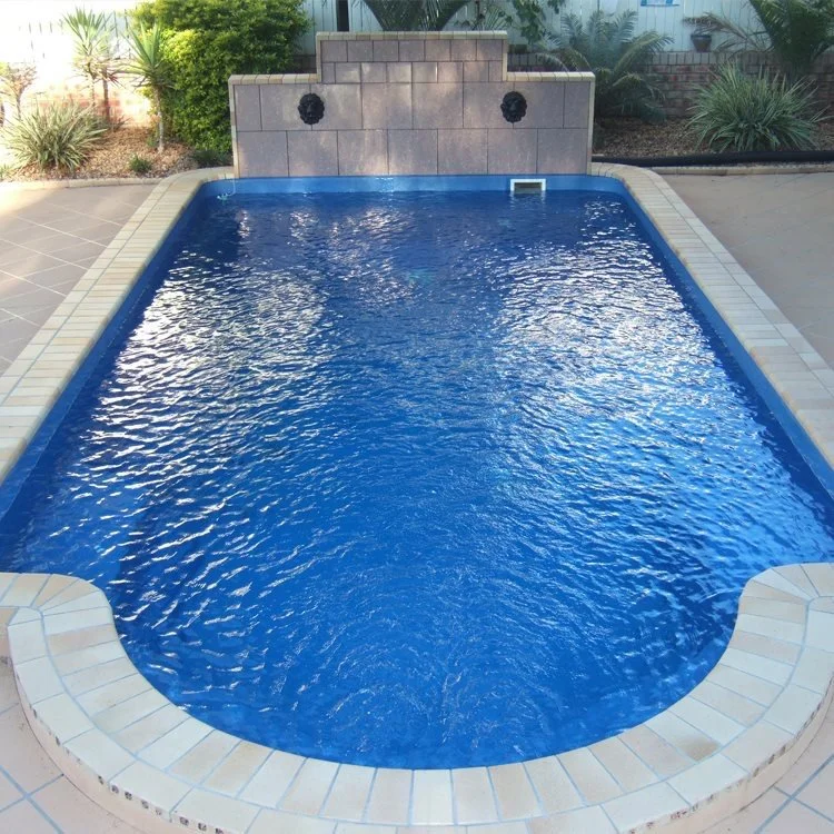 A small rectangular swimming pool with built-in water features on a patio surrounded by plants and landscaping.