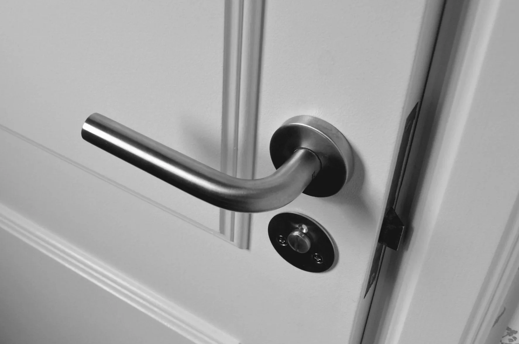 A close-up of a silver door handle and lock on a white door.