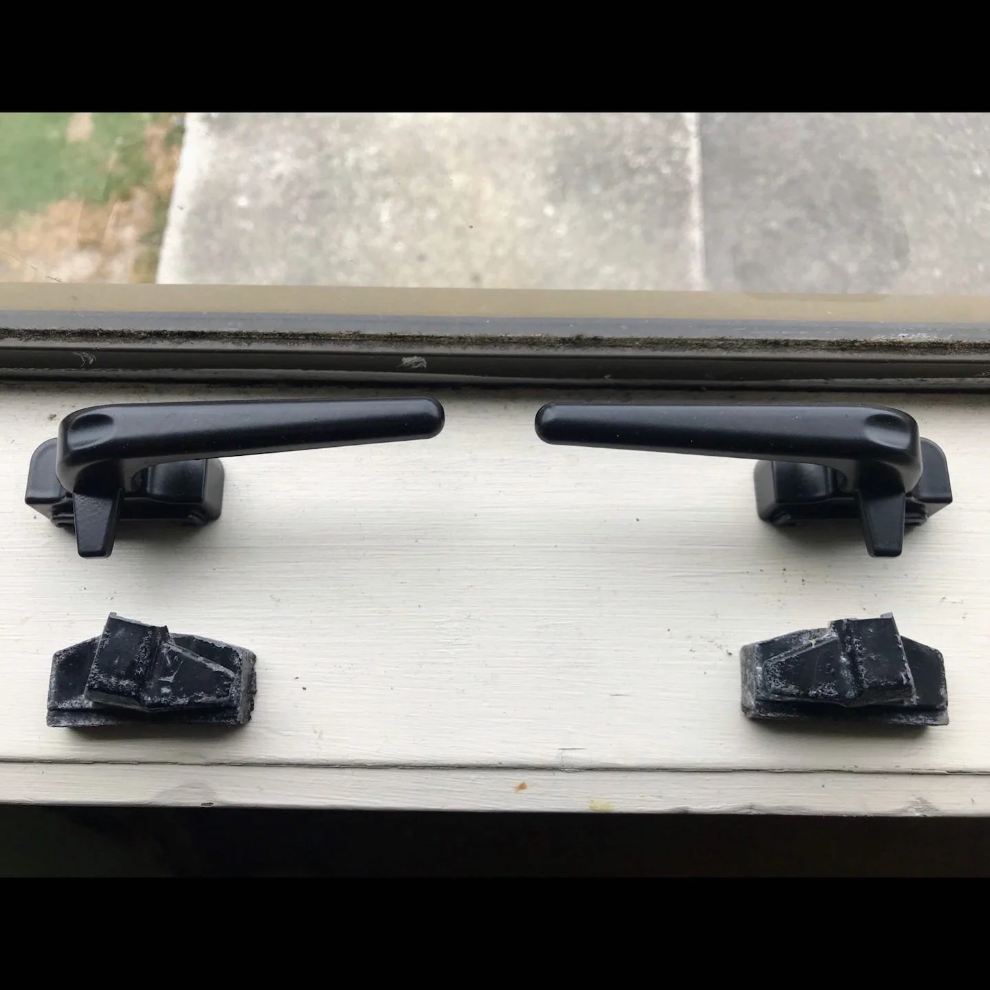 Black window or door handles with hardware on a white surface.