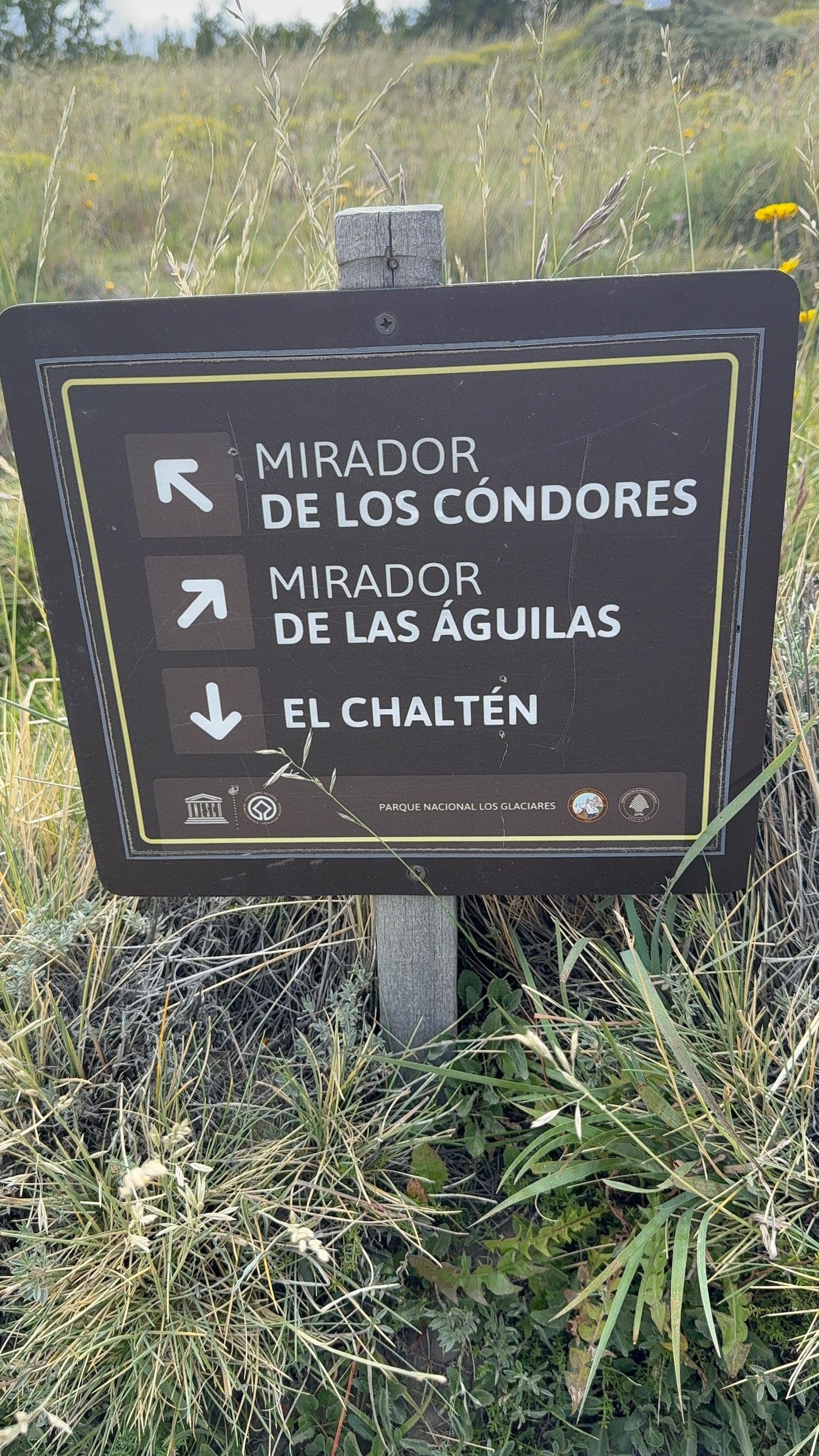 Trail sign in El Chaltén pointing toward Mirador de los Cóndores, Mirador de las Águilas, and the town.