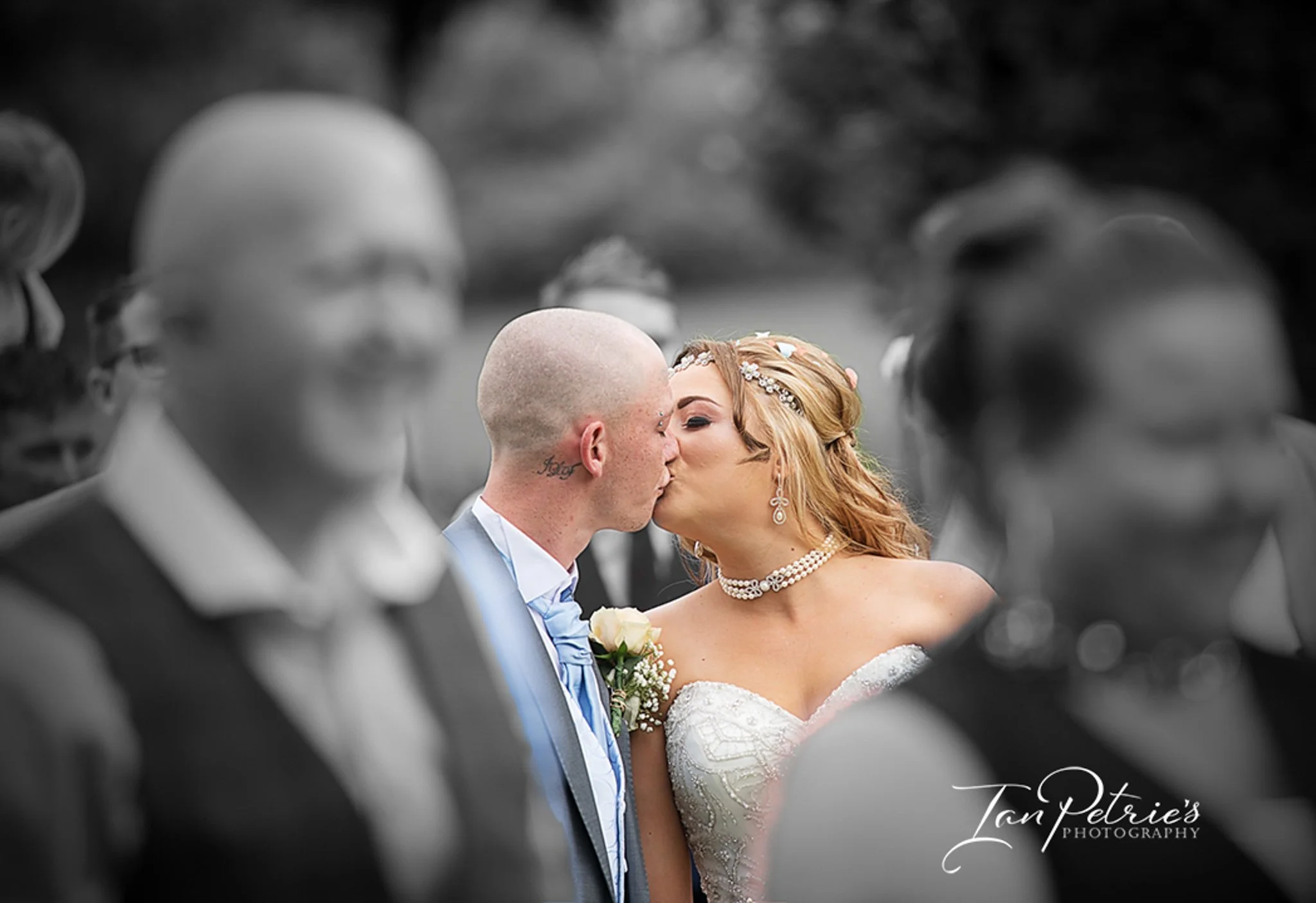 Naturally captured photo of the bride and groom kissing at Carr Bank Park Wedding Venue with friends around them,