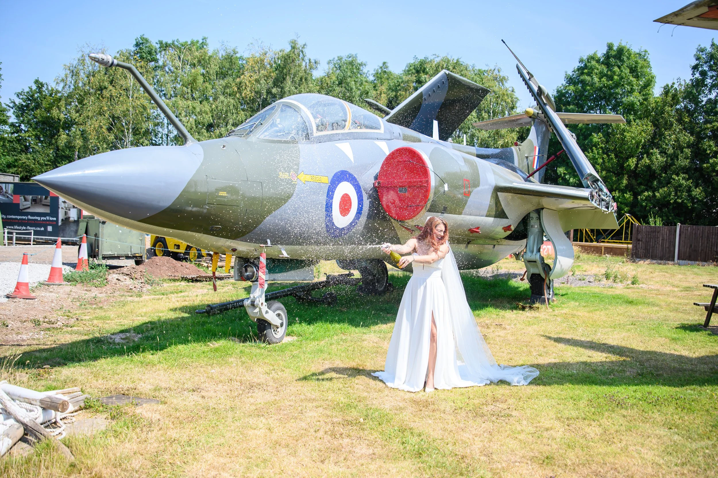 Bride spraying a bottle of bubbly in front of a jet plane.