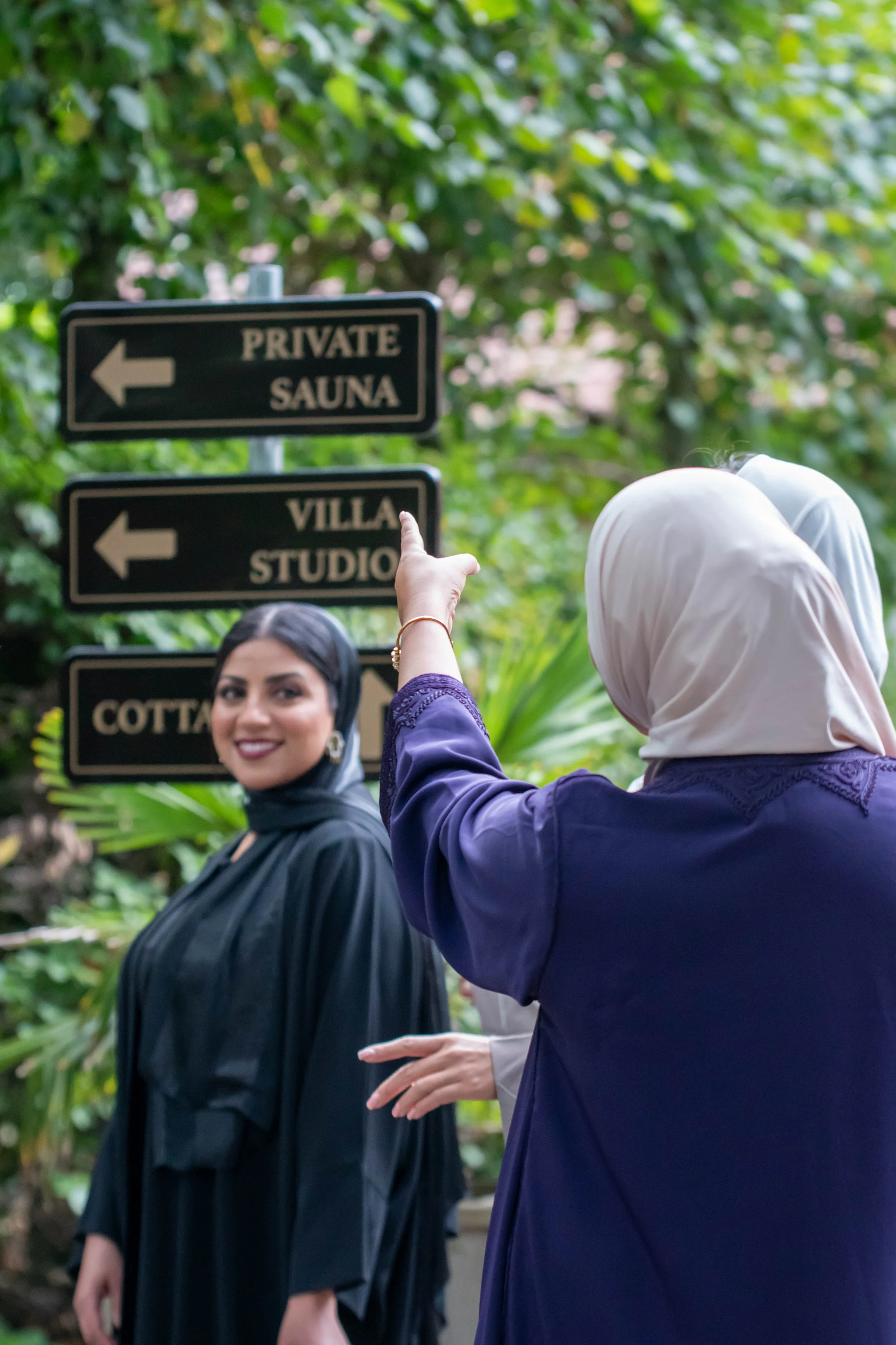 Twee vrouwen met hoofddoek bij de wegwijzer naar de Private Sauna op Landgoed Nardinclant in Laren
