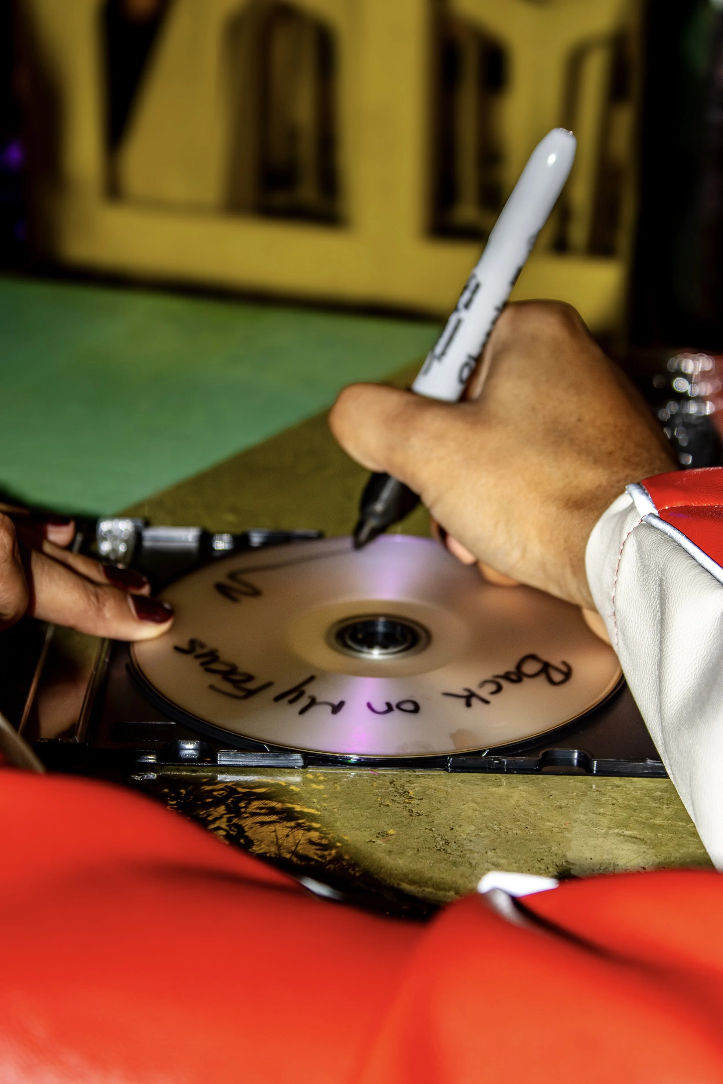 Person signing a disc with a black marker, with a message that reads 'Back on the beaches!'