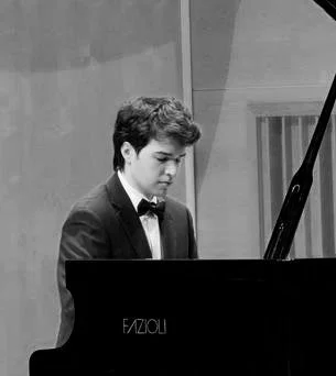Young man playing a grand piano in a recording studio or practice room.