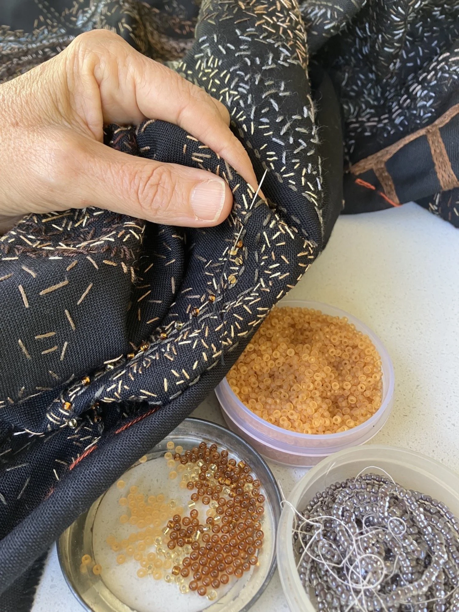 Tamar Mason adding beads to embroidered fabric