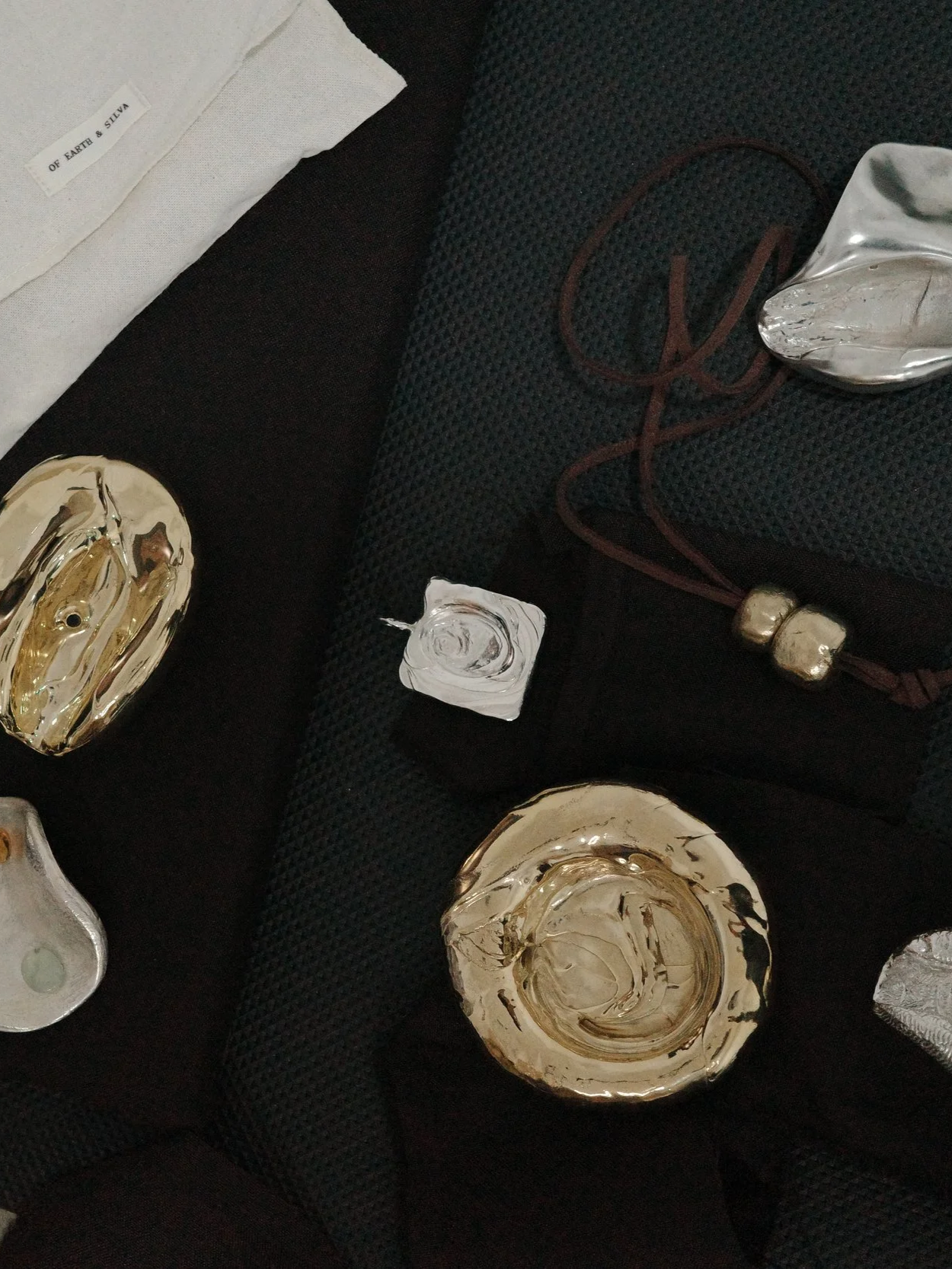 Decorative glass art pieces on a dark surface, including gold and silver-colored abstract bowls and sculptures.