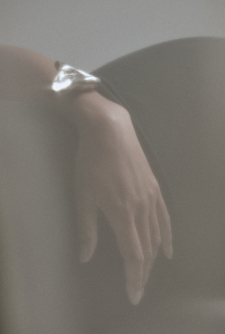 A hand with a ring on the finger, seen through a foggy or blurred effect.