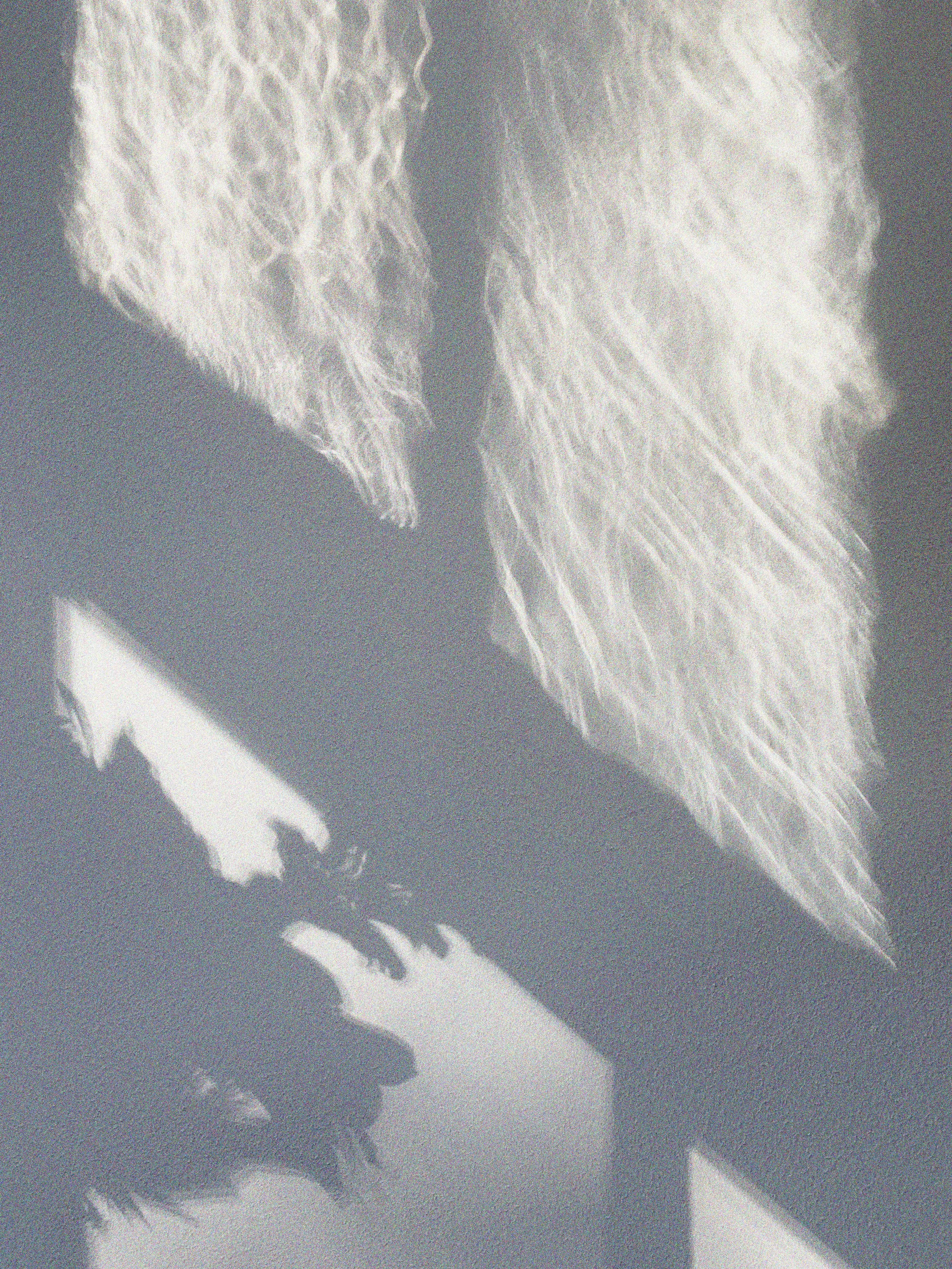 Close-up of a piano keyboard with white and black keys and a shadow cast on a textured surface.