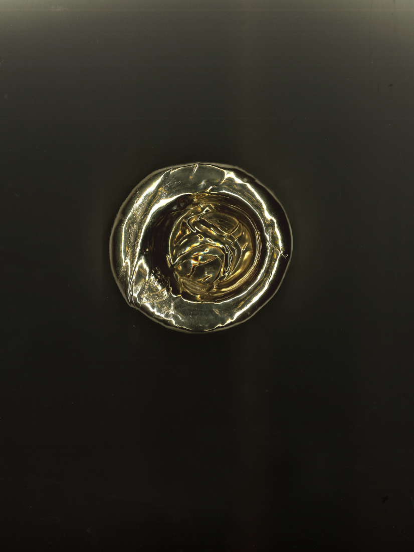 A top-down view of a glass of whiskey on a black surface.