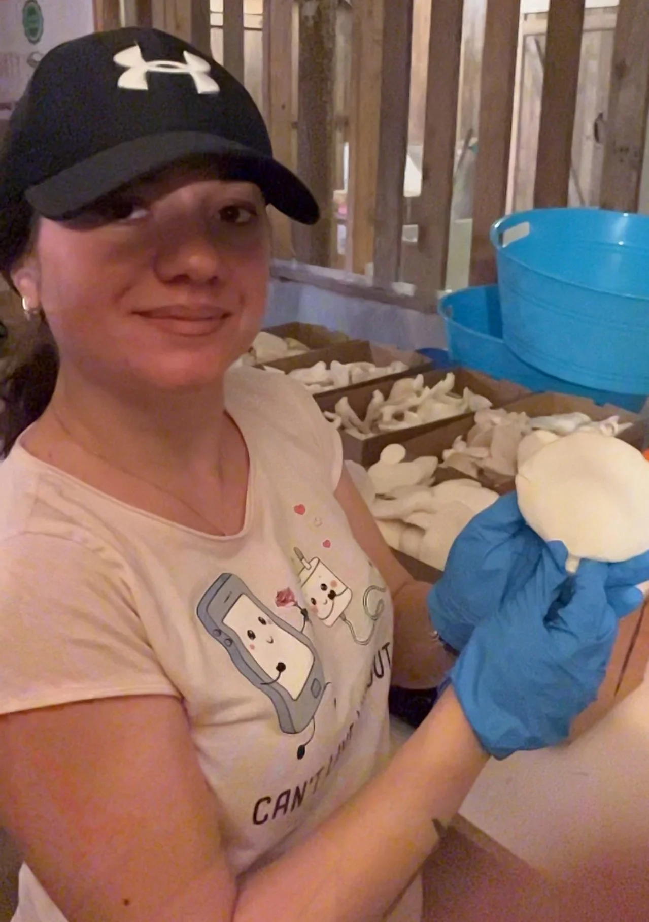 A woman wearing a beige T-shirt holding oyster mushrroms in a box