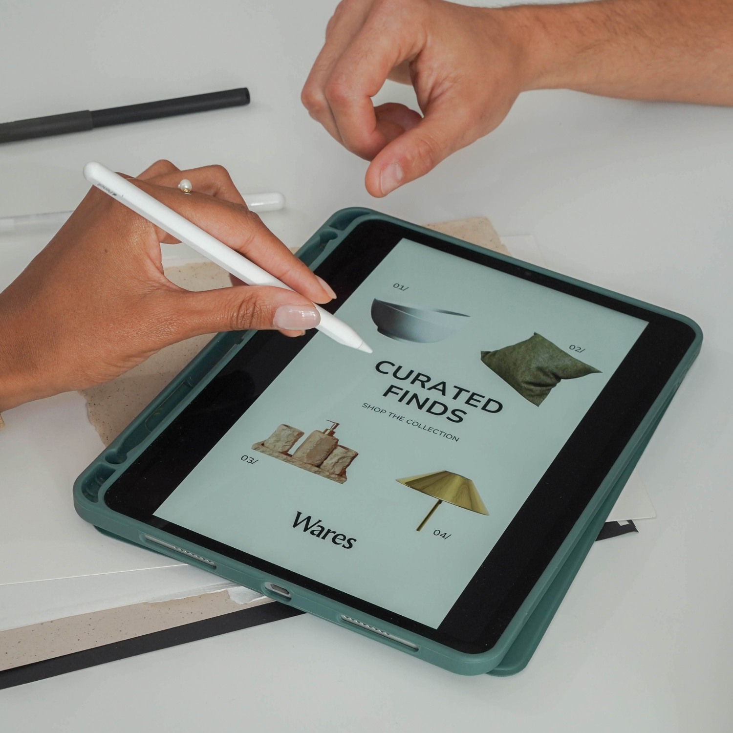 Person using a tablet with a stylus, displaying a webpage titled 'Curated Finds' featuring home decor items like a bowl, pillow, soap dispenser, and lamp.