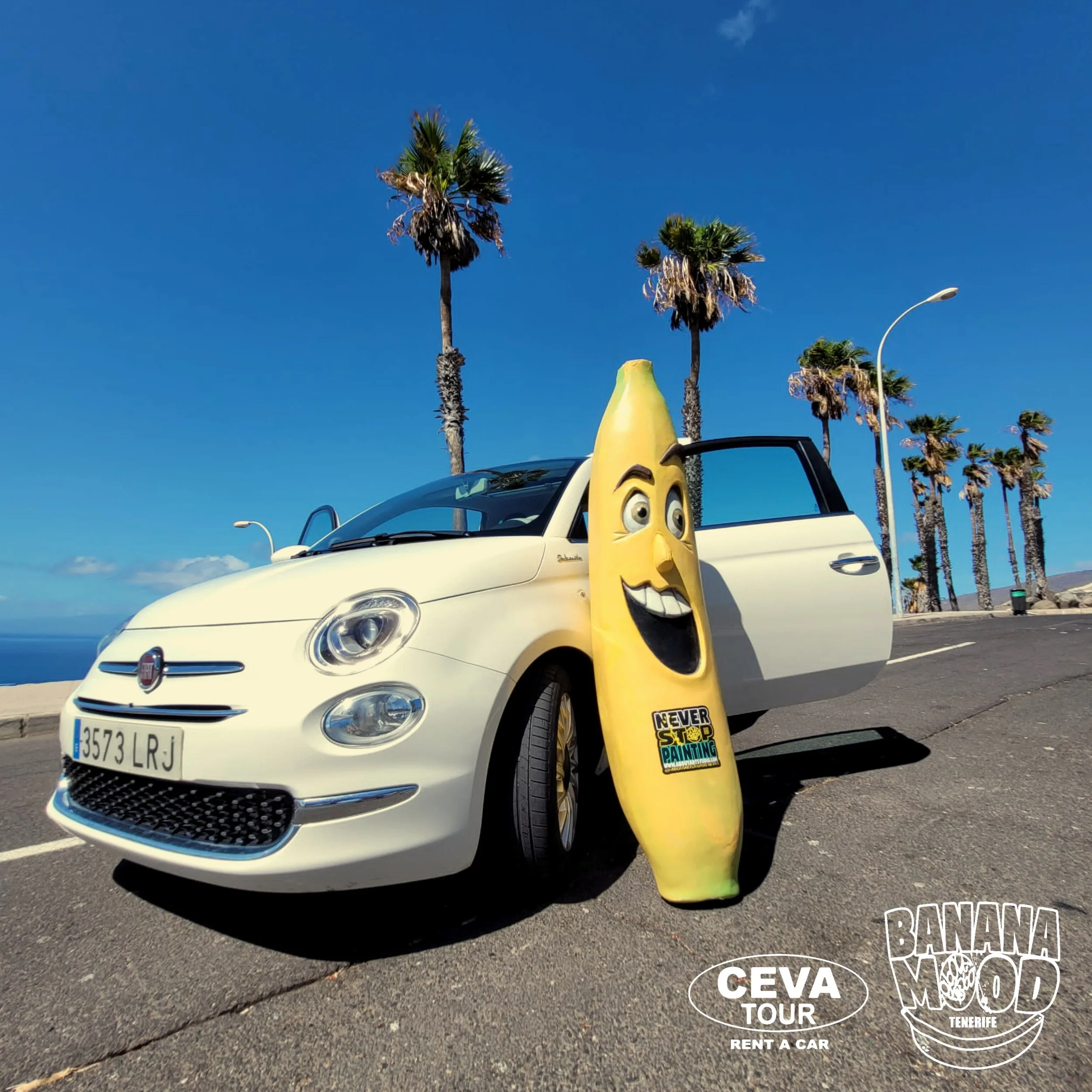 Coche blanco estacionado en la calle con palmeras de fondo, con una banana de cartel con cara sonriente a su lado y logotipos de CEVA Tour y Banana Mood Tenerife.