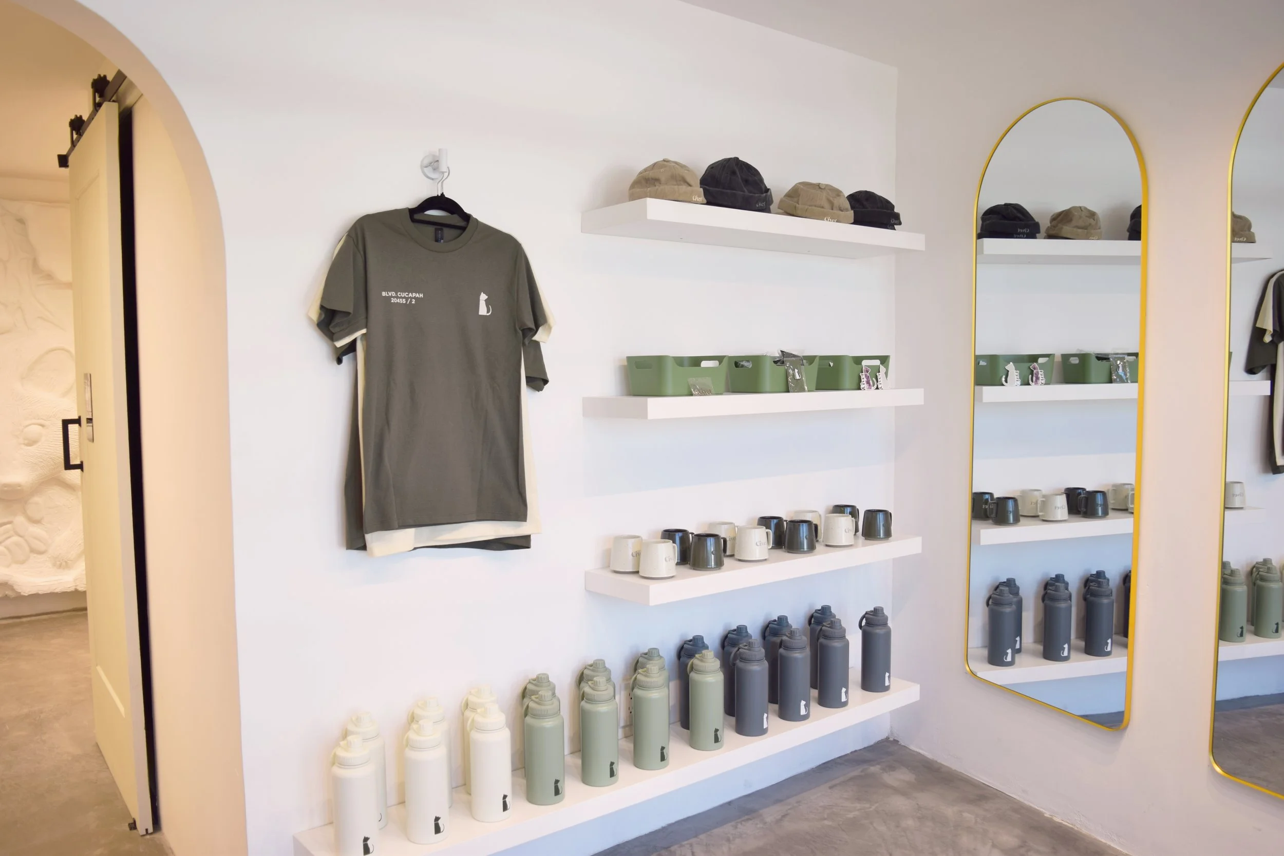 Estanterías con camisetas, sombreros, tazas y botellas de agua en una tienda