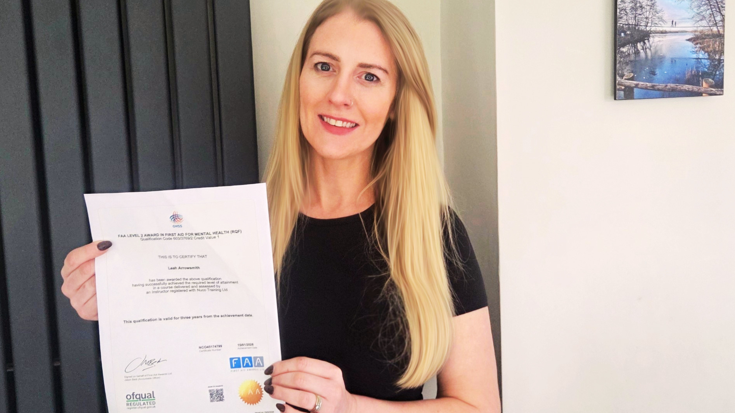 Image shows Leah Arrowsmith holding a certificate for the Mental Health First Aid qualification.