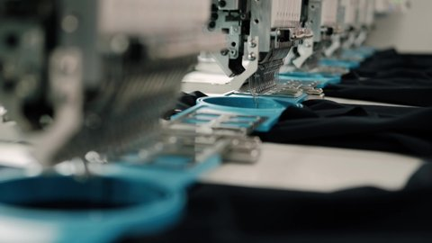 Close-up view of an industrial embroidery machine stitching fabric with blue thread.