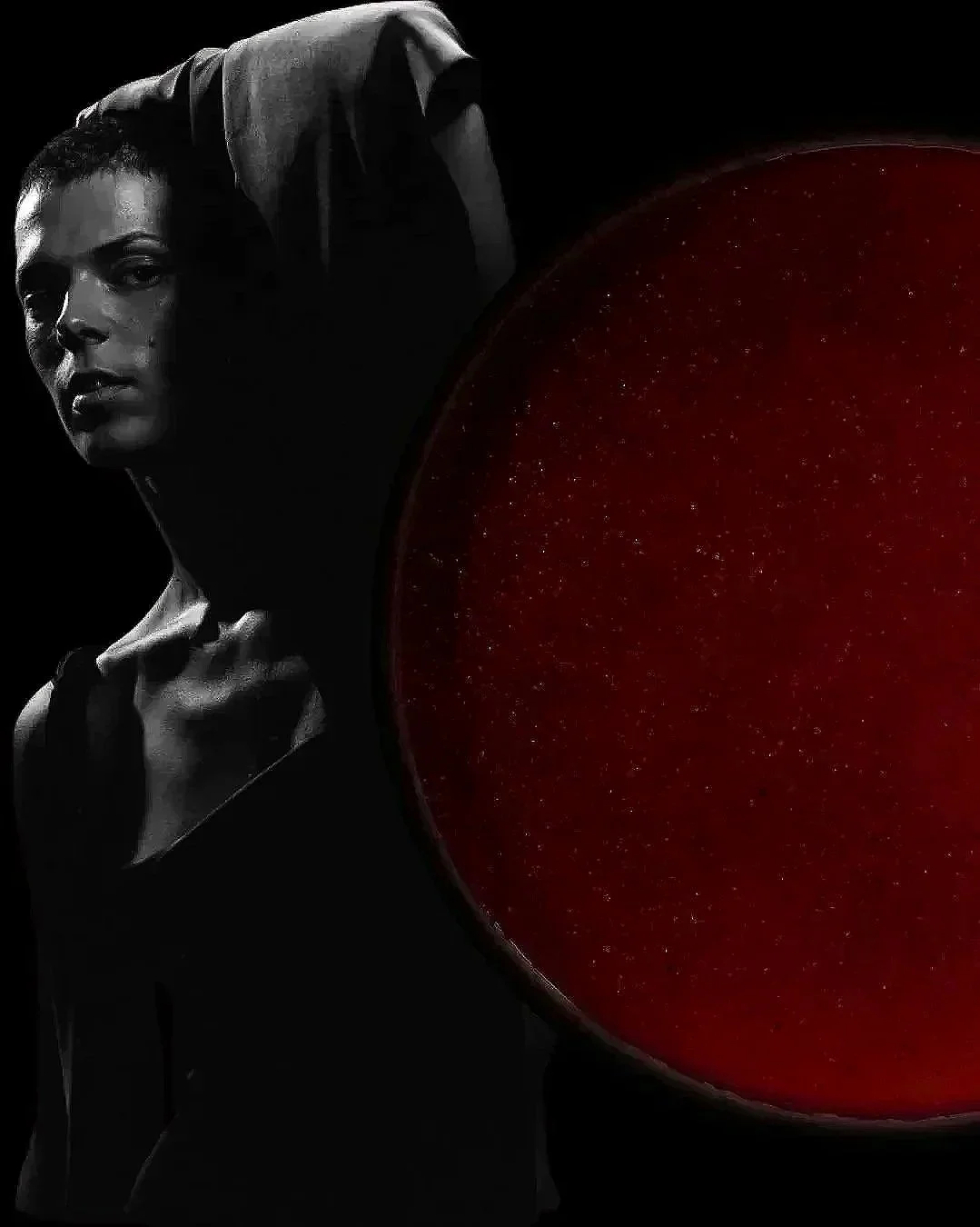 A woman in black and white on the left side looking confident, with a large red circular object on the right side covering part of the image.