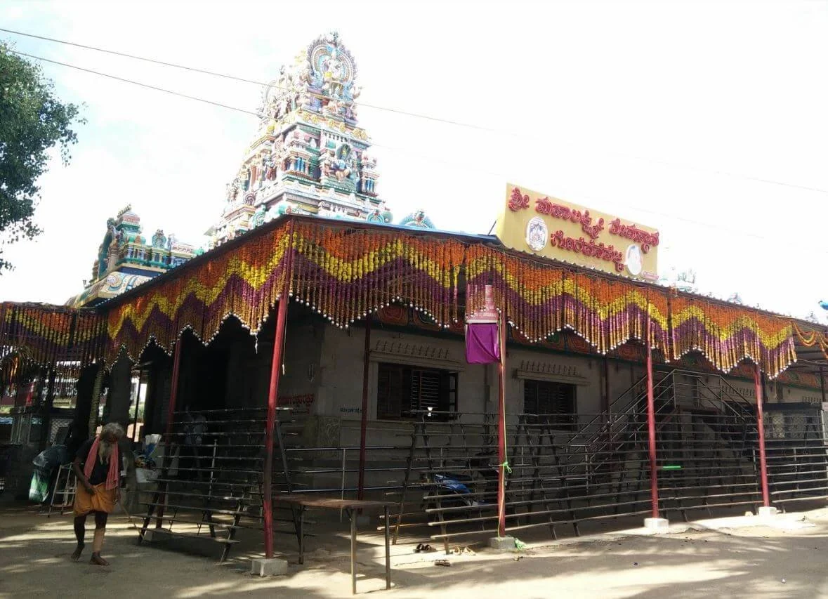 Hindu temple with colorful decorations and a gopuram (tower) in the background, with a person walking nearby.