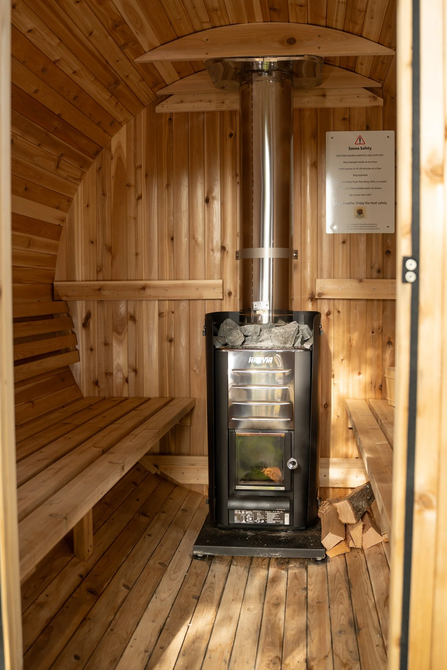 Cozy sauna interior with Harvia wood stove and benches ready for guests to unwind during a wellness retreat in Narragansett RI
