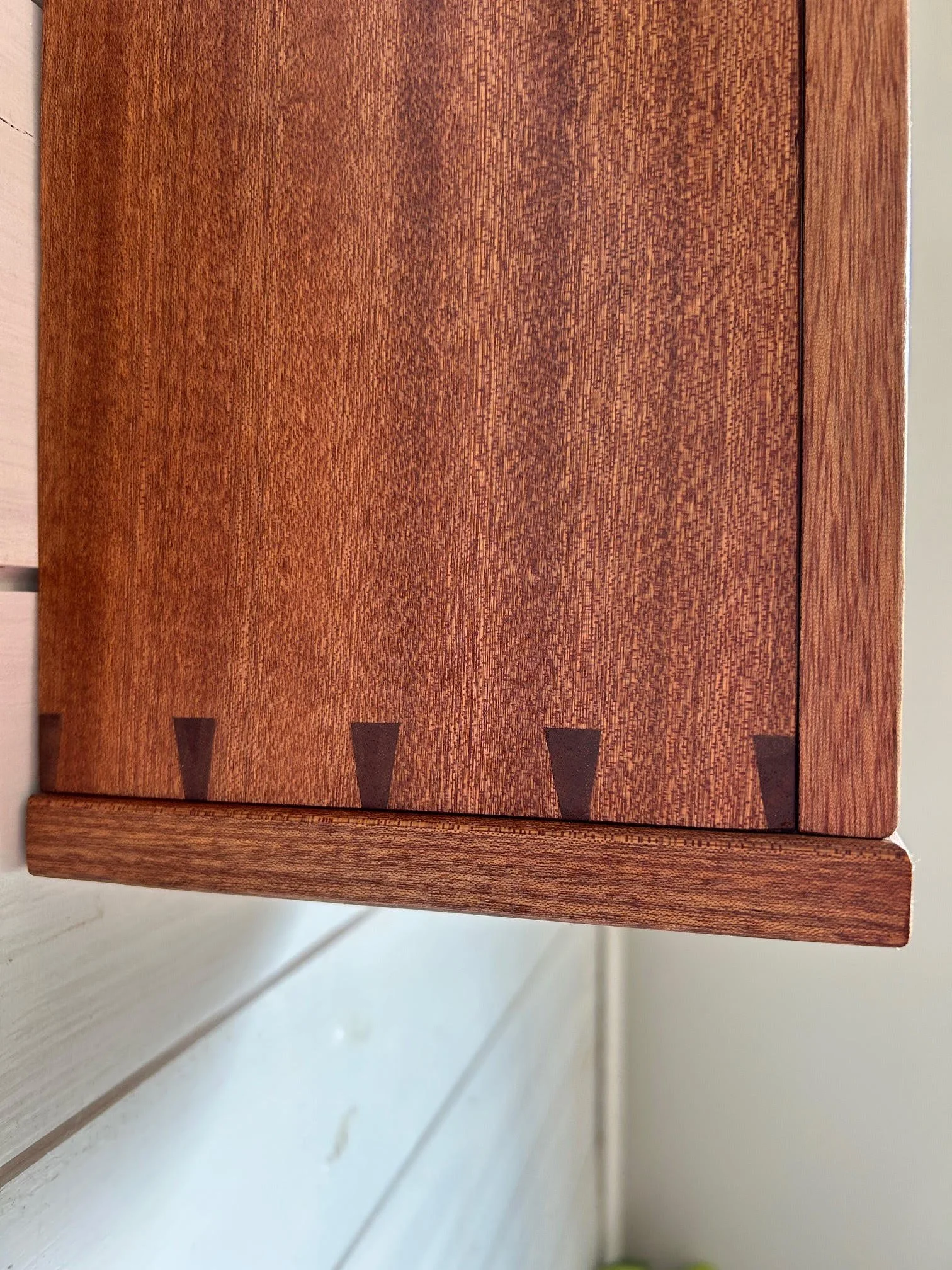 Close-up of a wooden piece of furniture with a smooth surface and decorative inlay detailing along the edge.