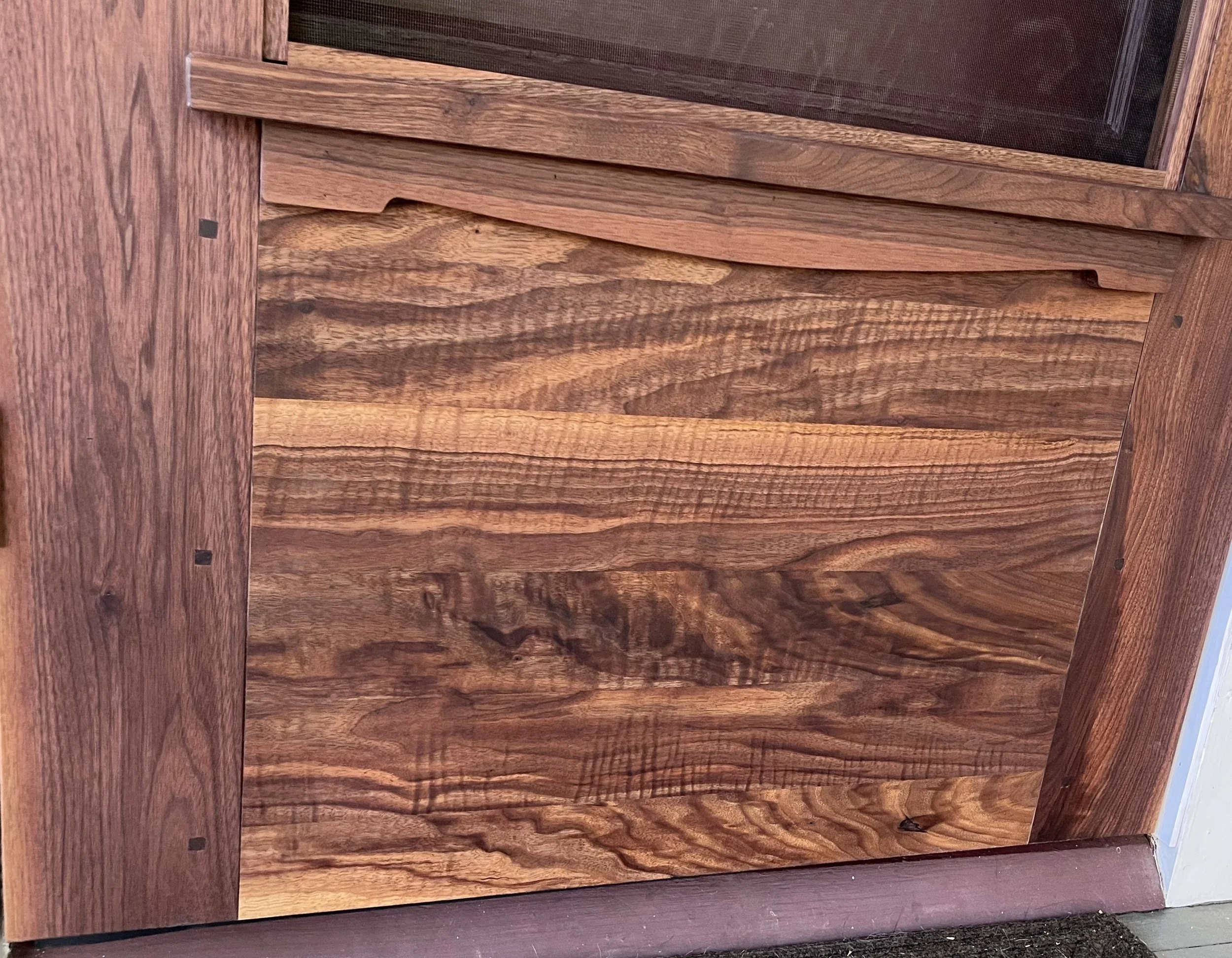 Close-up view of a wooden cabinet door with a natural wood grain pattern and a horizontal grain orientation.
