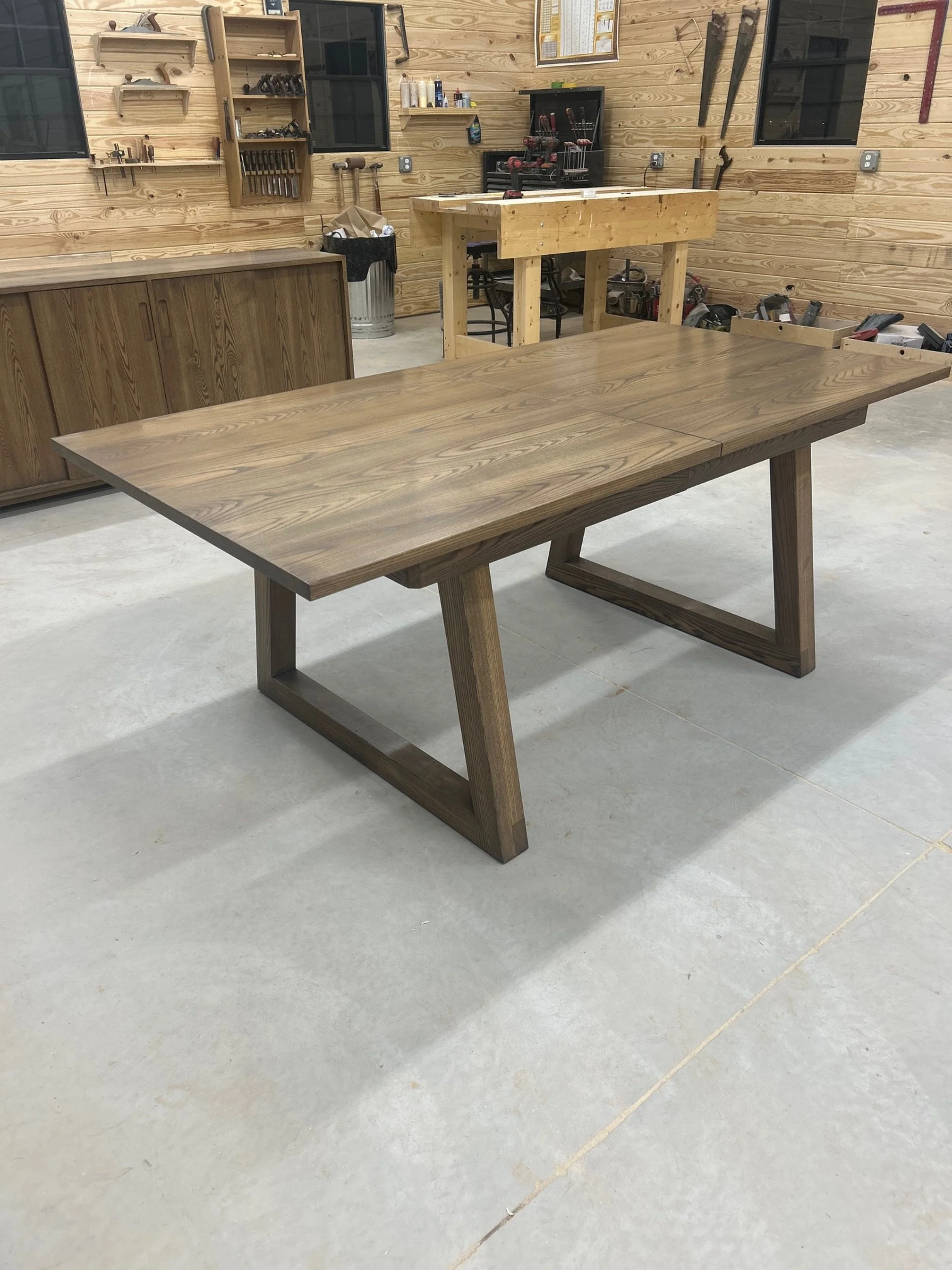 A modern wooden dining table with a natural finish in a woodworking workshop.