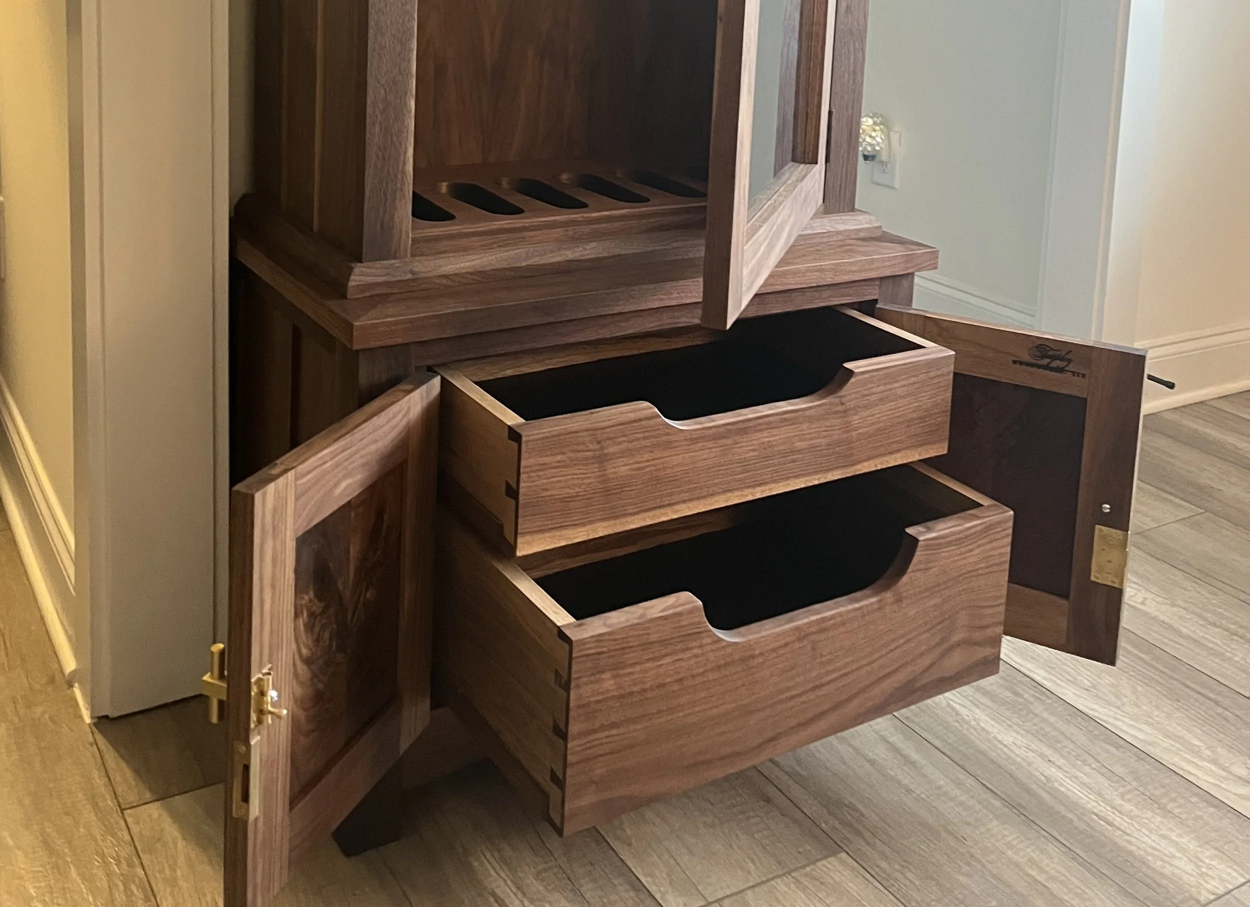 Wooden cabinet with open doors and drawers, showing shelving and storage space inside.