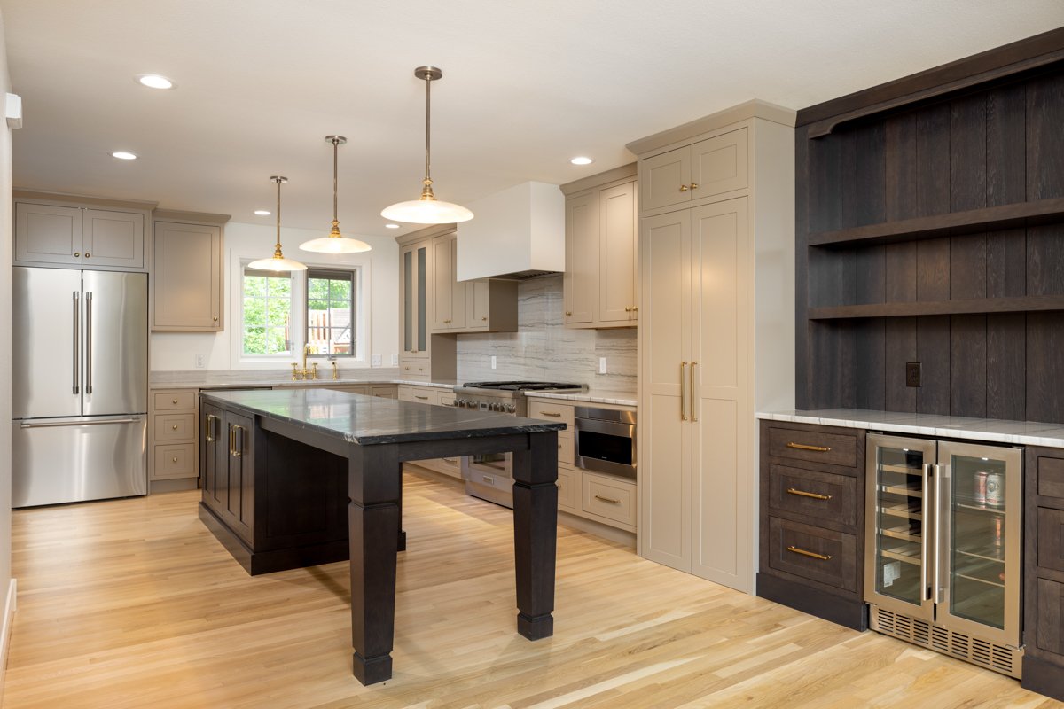 Modern kitchen with stainless steel refrigerator, island with dark countertop, beige cabinetry, and a wine cooler