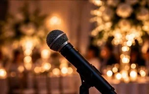 A black microphone on a stand with blurred festive lights in the background.