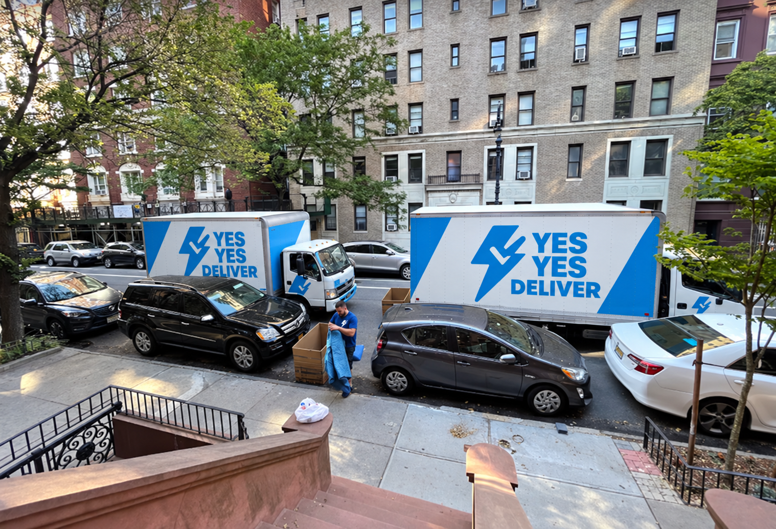 Two Yes Yes Deliver moving trucks outside a Brooklyn apartment building as a mover prepares for a residential move.