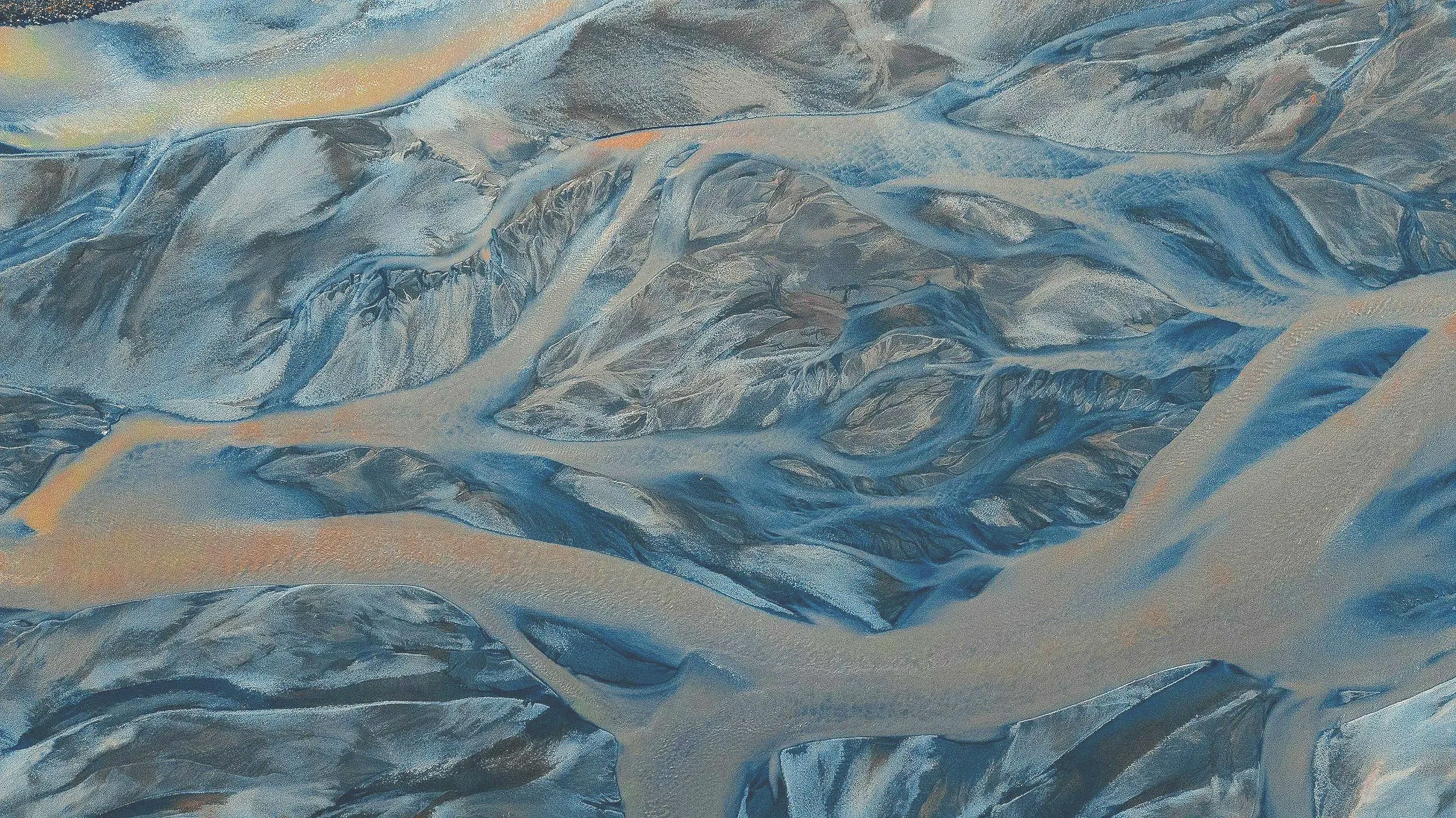 Aerial view of snow-covered mountain range with ridges and valleys.
