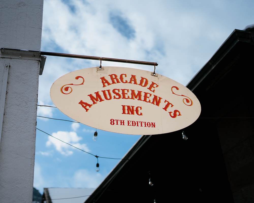 Close-up photo of the Arcade Amusements sign in Manitou Springs, highlighting vintage typography against a bright Colorado sky.
