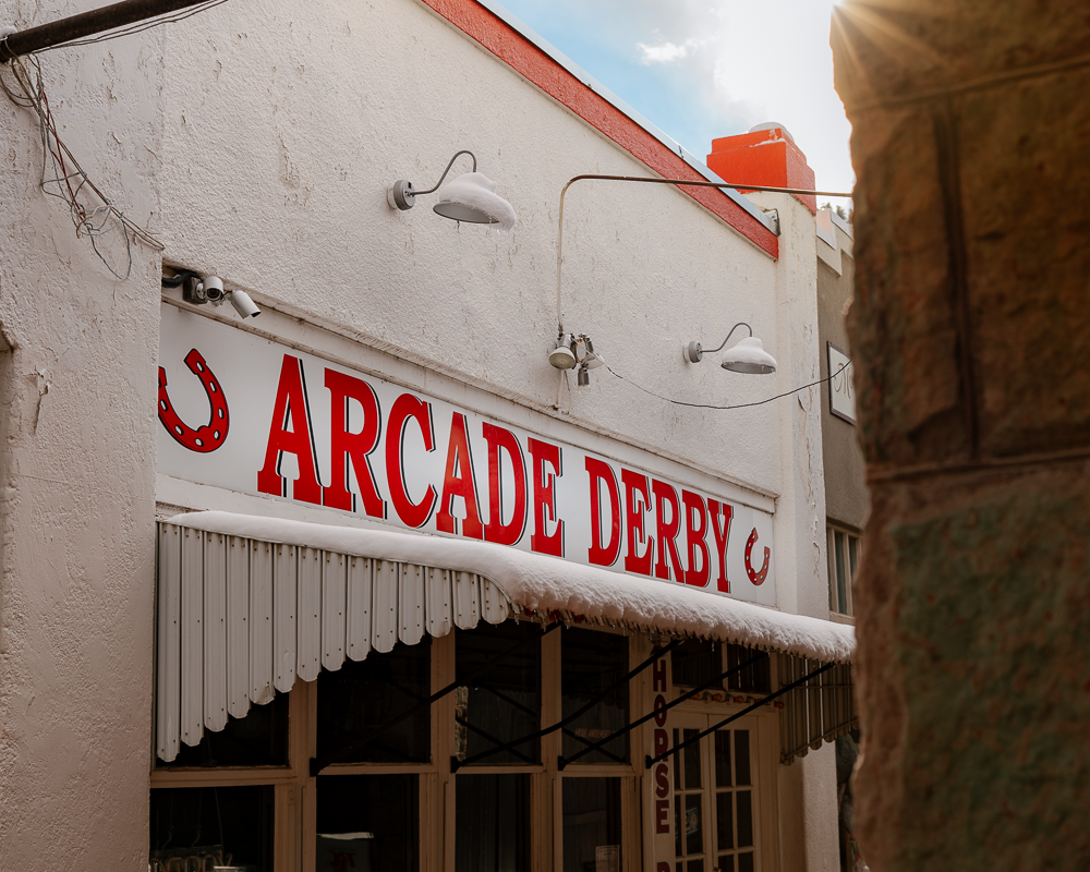 Arcade Derby sign in Manitou Springs photographed with warm sunlight and winter accents, highlighting local attractions and vintage character.